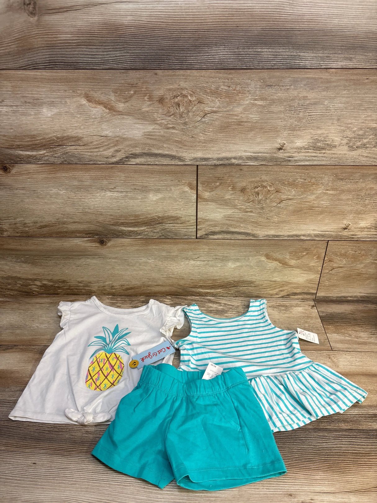 Toddler girl outfit set with pineapple graphic tee, turquoise shorts, and striped dress.
