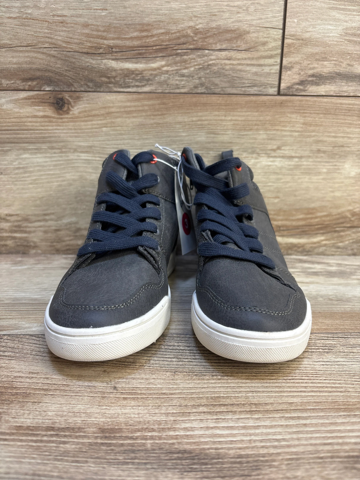 Children's dark gray lace-up sneakers with white soles on wood background