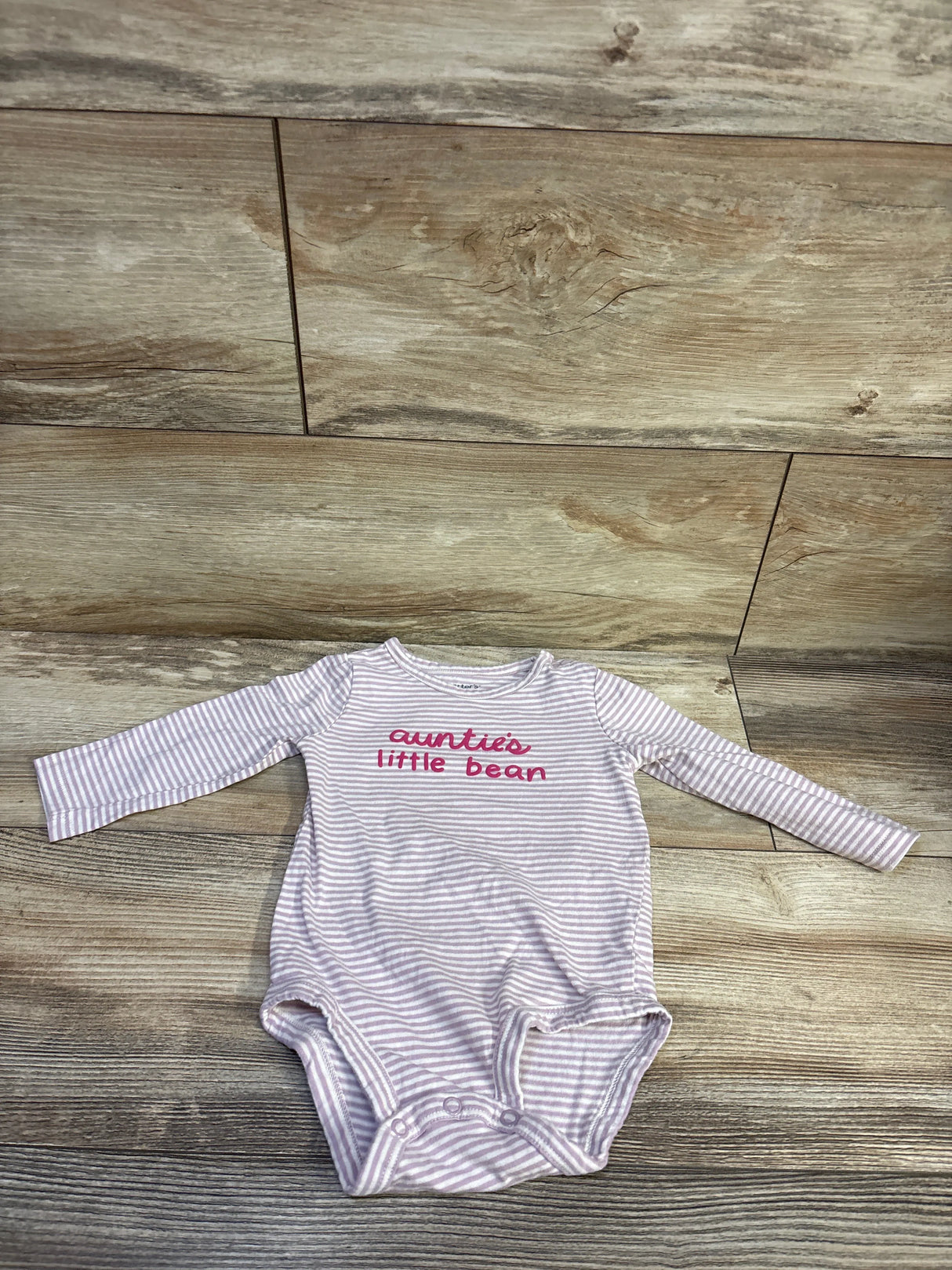 Front view of Carter’s purple Auntie’s Little Bean bodysuit showcasing stripes and long sleeves on wood flooring