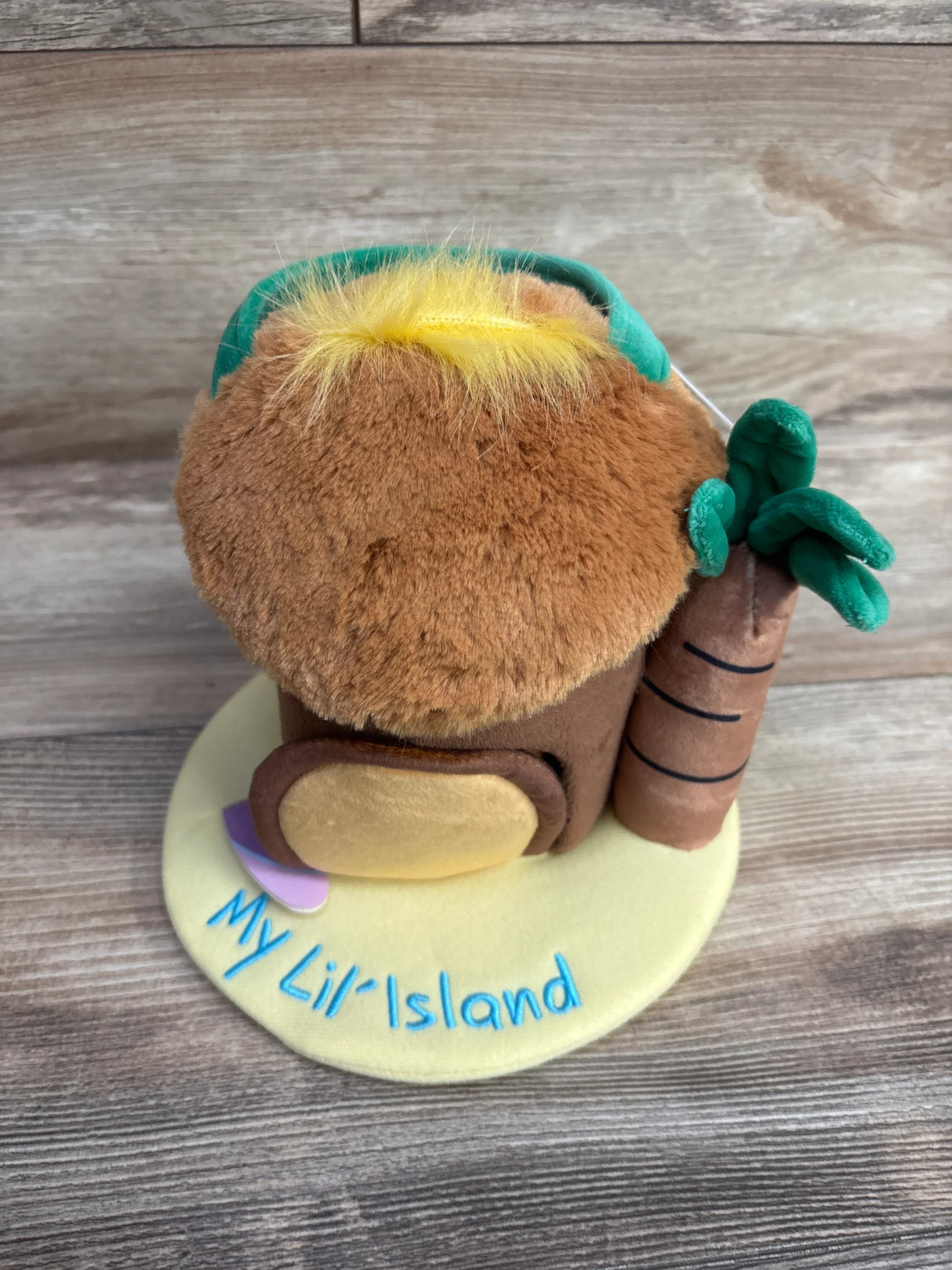 Plush toy house with brown roof, green leaves, and yellow base with My Lil' Island text on wood surface