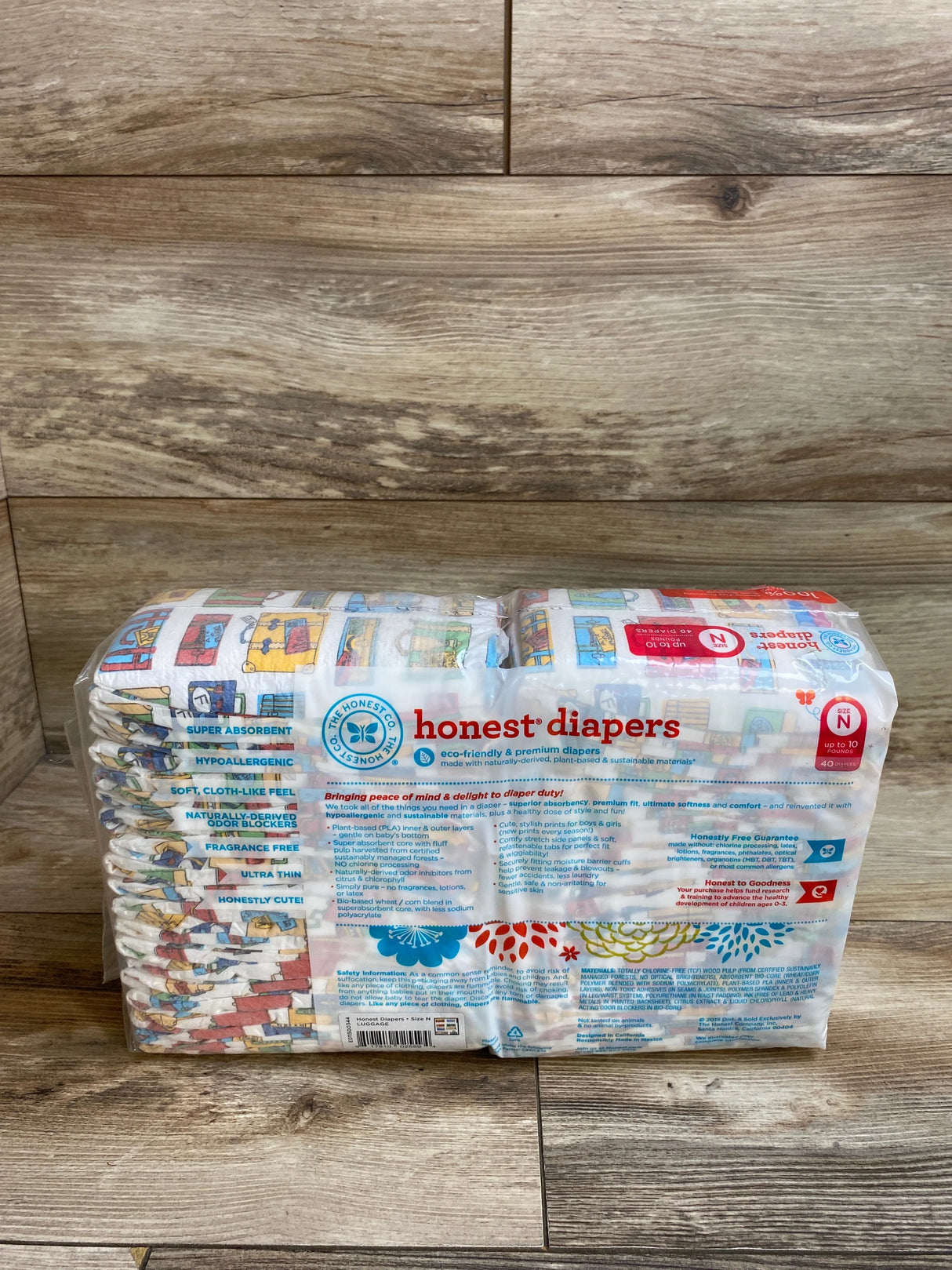 Pack of Honest diapers size N with colorful prints on wooden floor, eco-friendly and hypoallergenic