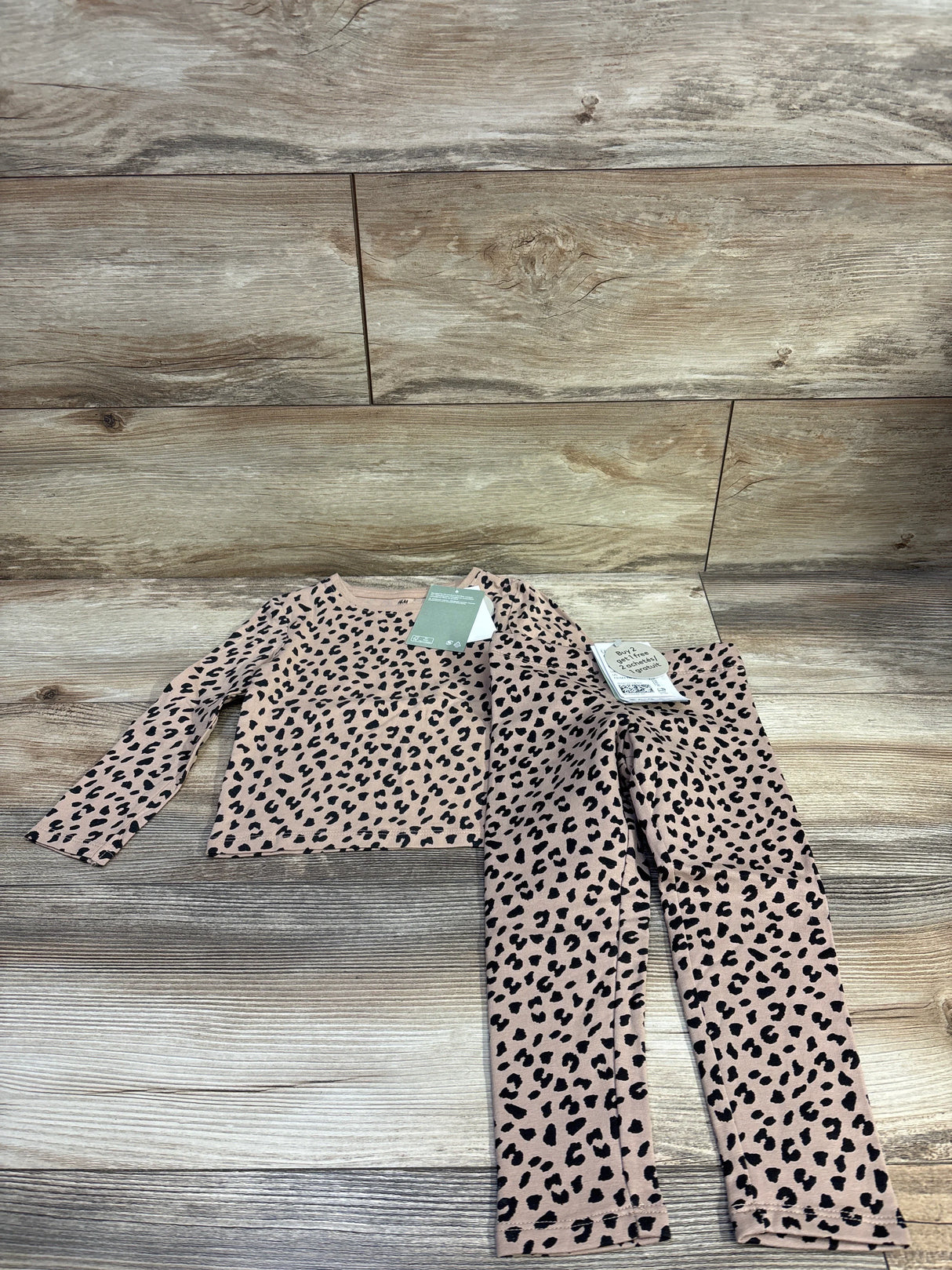 Flat lay of H&M toddler two-piece leopard print long-sleeve shirt and lined leggings, size 2T, on wood plank background