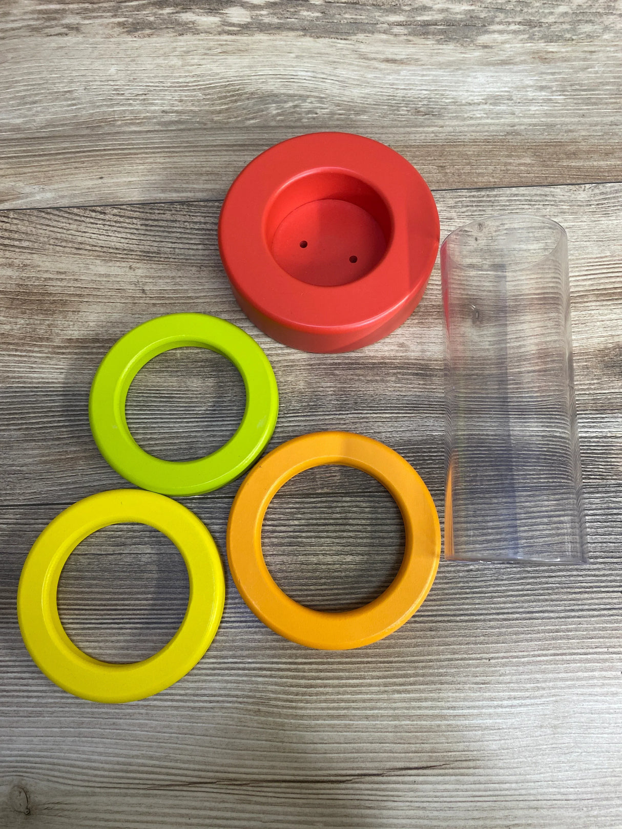 Colorful plastic stacking toy rings with base on wood surface, kids educational toy