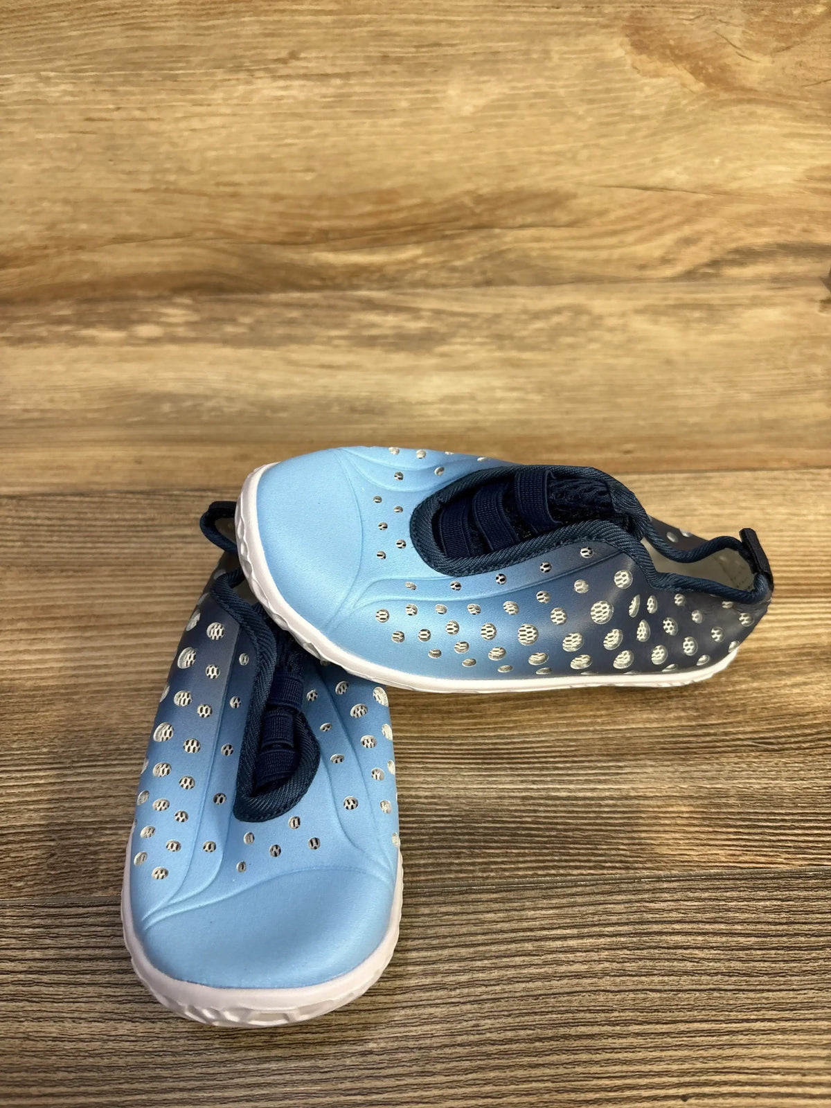 Angled top view of Fires Barefoot water shoes, quick-dry blue, size 11C; perforated upper and white sole on wood background