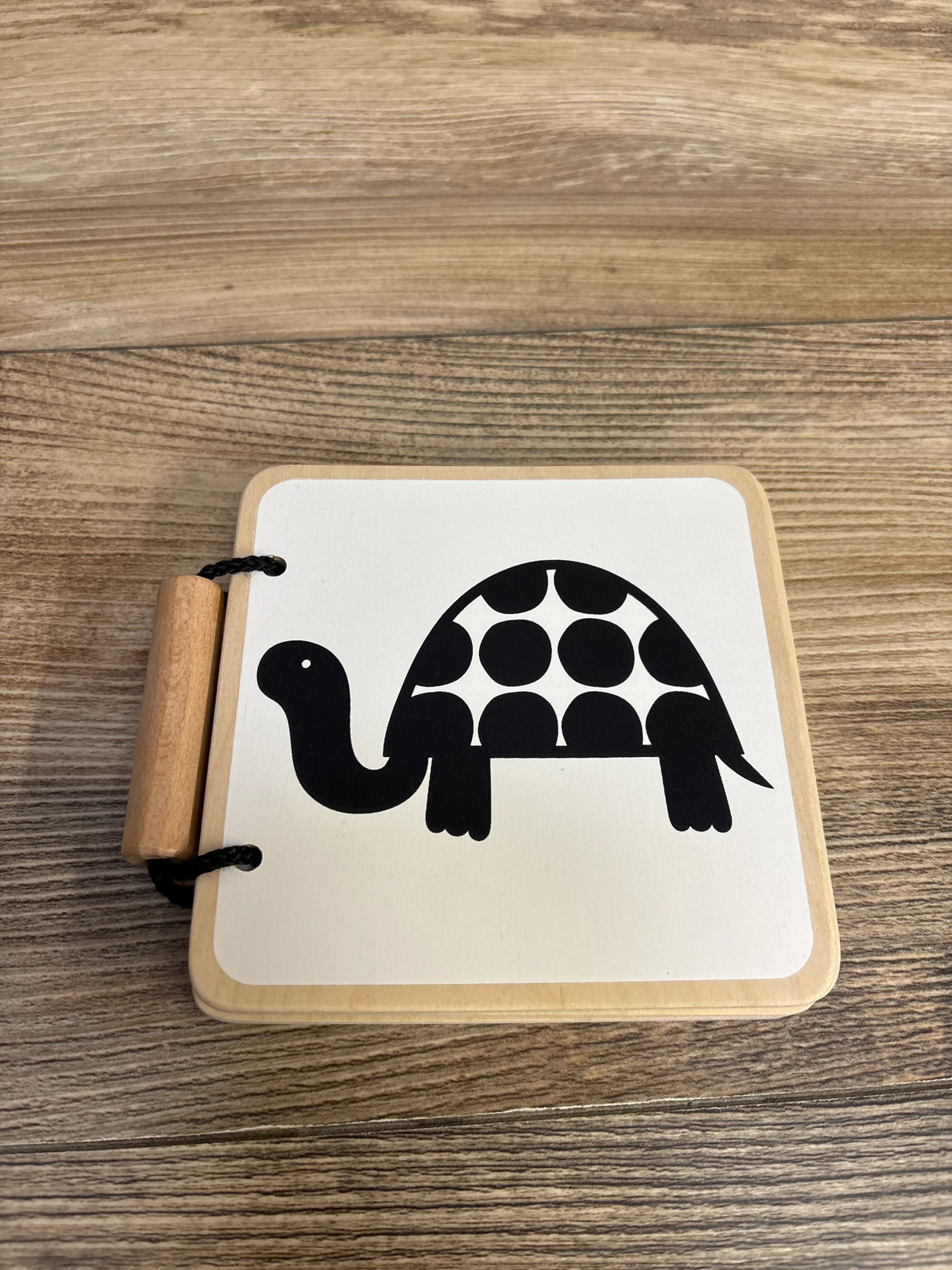 Black and white turtle illustration on a wooden flashcard with wood grain background