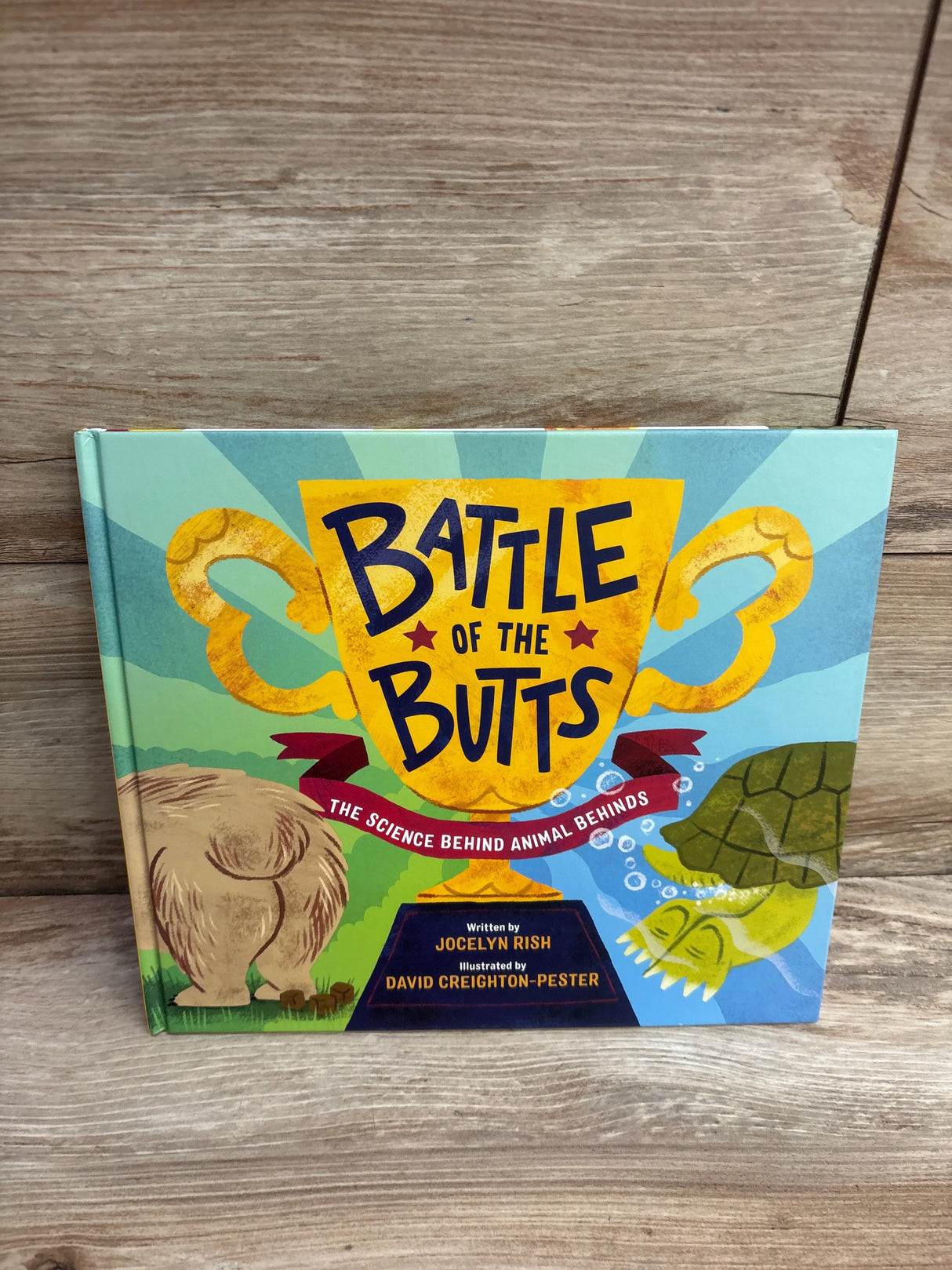 Battle of the Butts children's science book with colorful animal illustrations on wood background