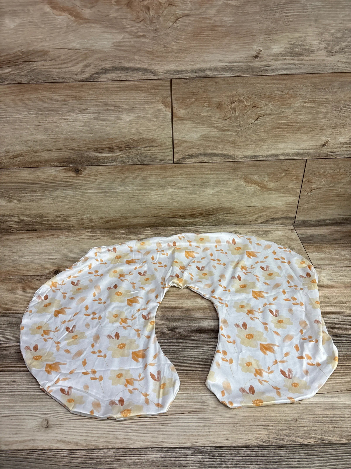 Top view of Woodiville nursing pillow cover showcasing its white floral pattern on a wood plank background
