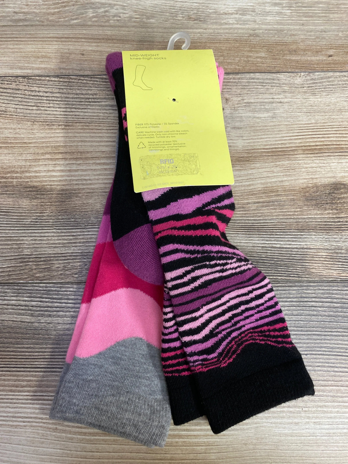 Pair of mid-weight knee-high socks with pink, purple, gray, and black patterns on wooden surface