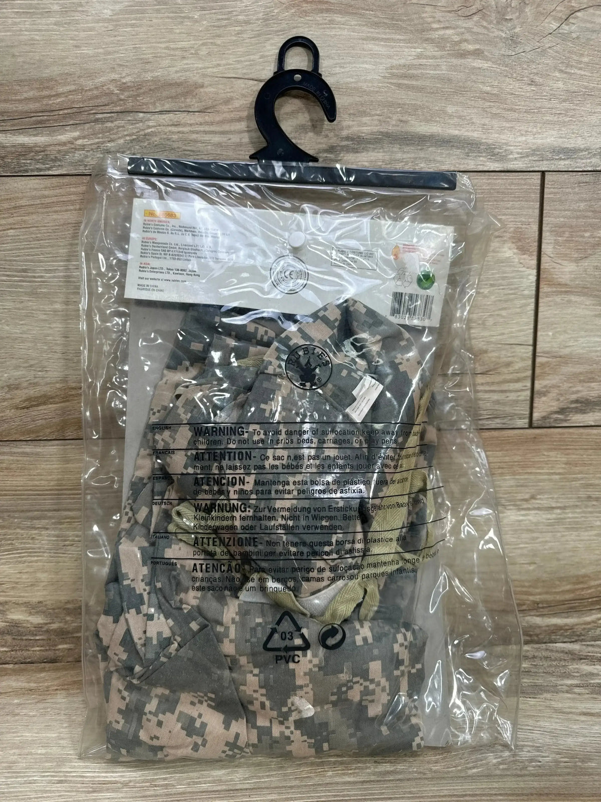 Front view of Rubie’s soldier bunting costume in camouflage packaging with hanger on a wood floor