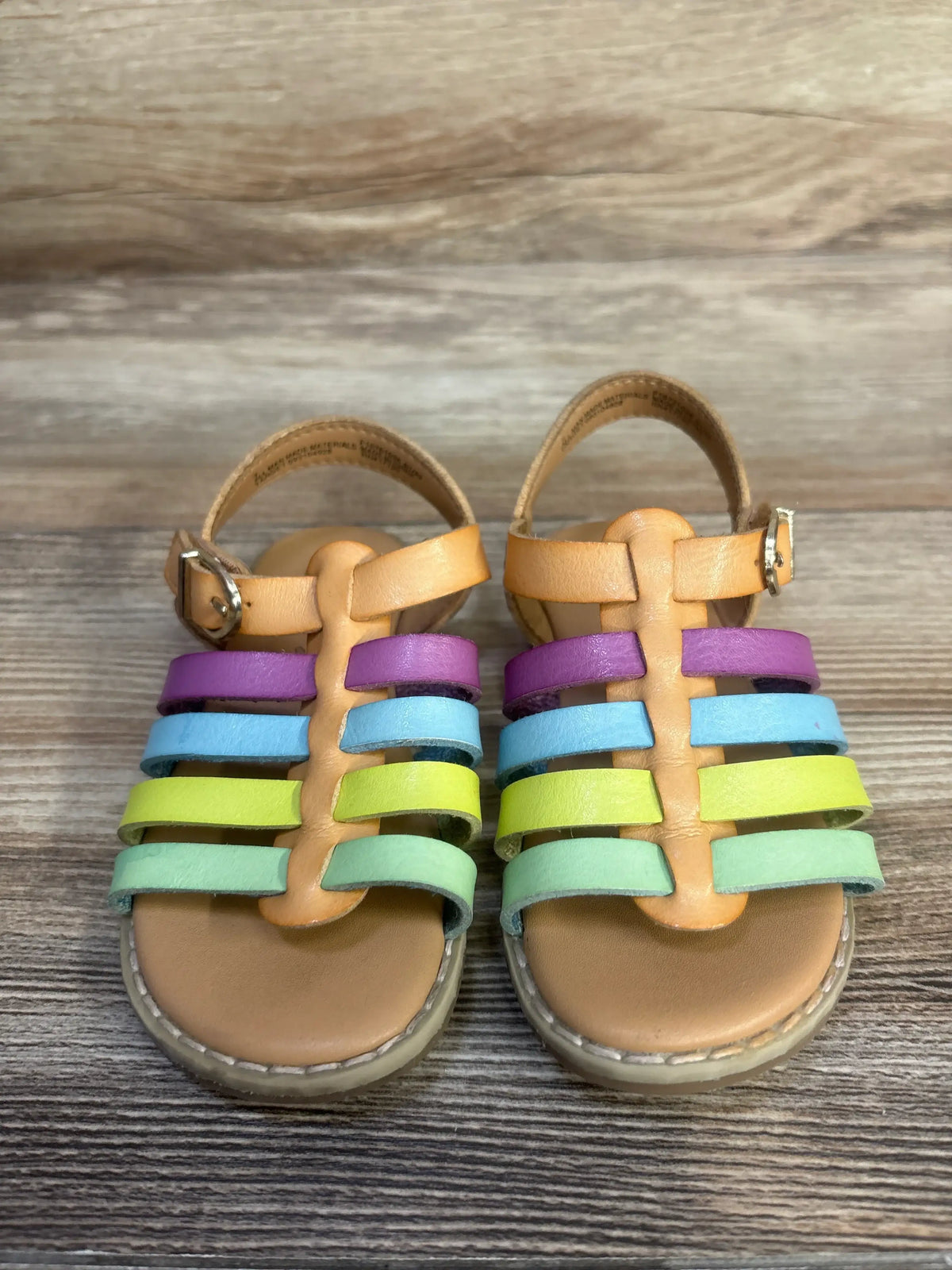 Front view of Cat & Jack Shanel fisherman sandals showcasing multicolored straps and hook and loop closures on wood