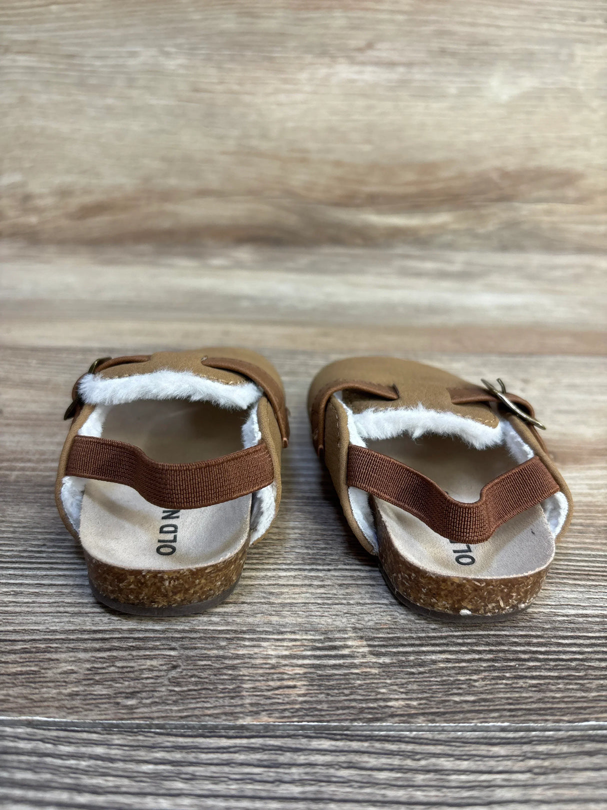 Brown toddler sandals with shearling lining and cork soles on wood background