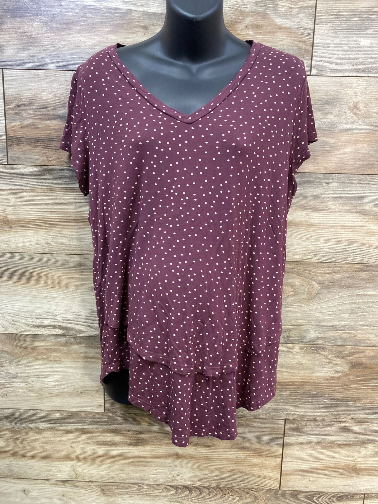 Burgundy polka dot short sleeve V-neck blouse on mannequin, wood panel background