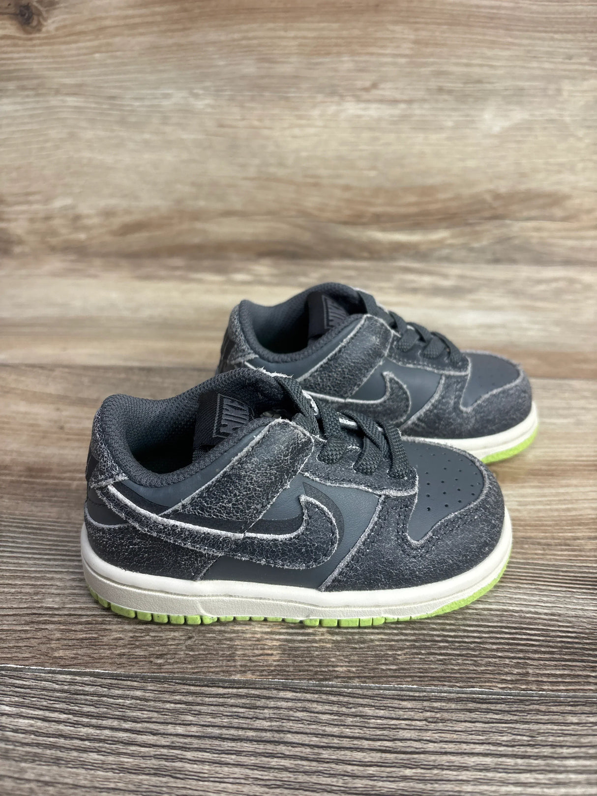 Black toddler Nike sneakers with green sole, resale kids shoes on wood floor