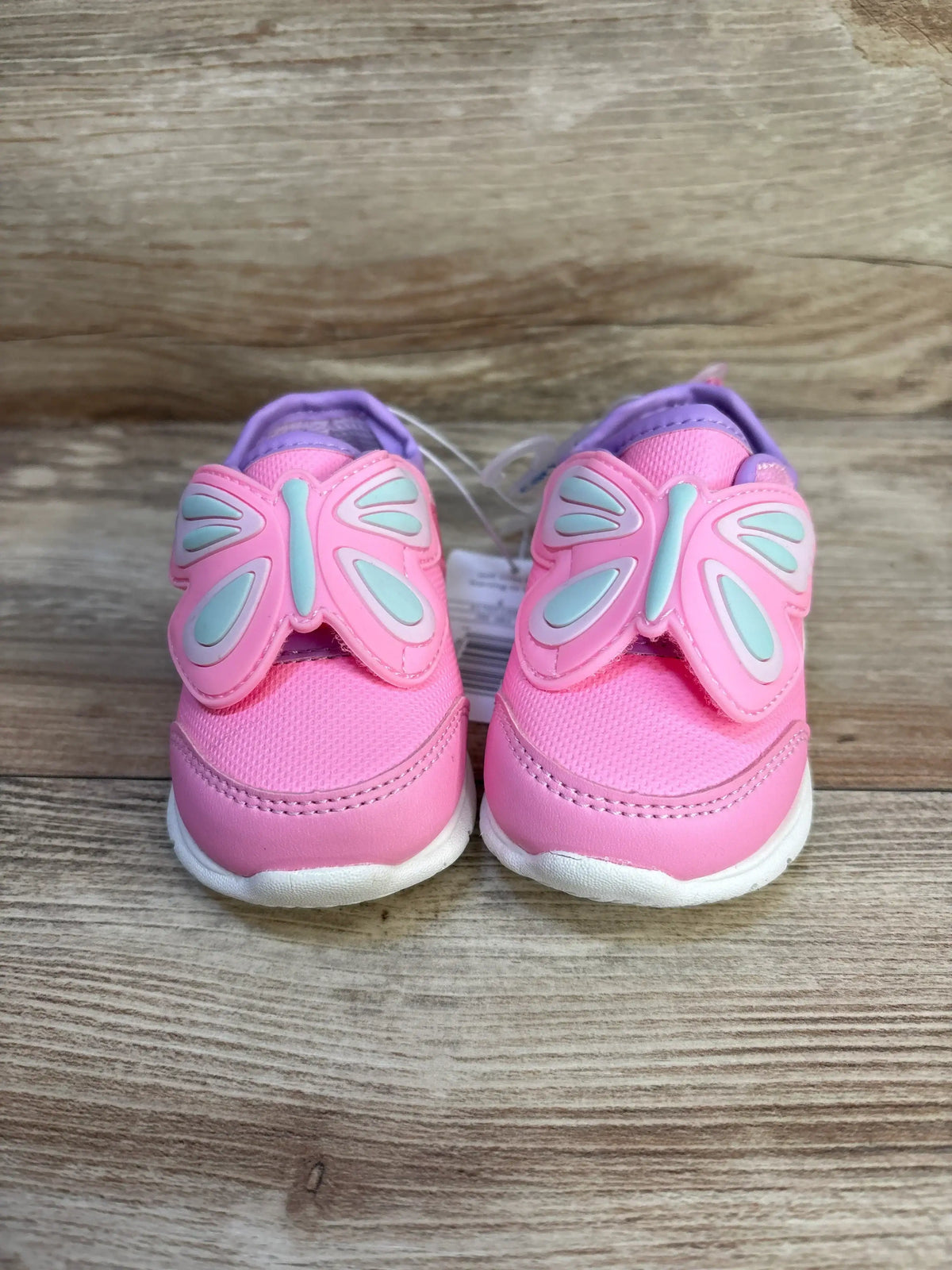 Pink toddler shoes with butterfly wings on wooden background