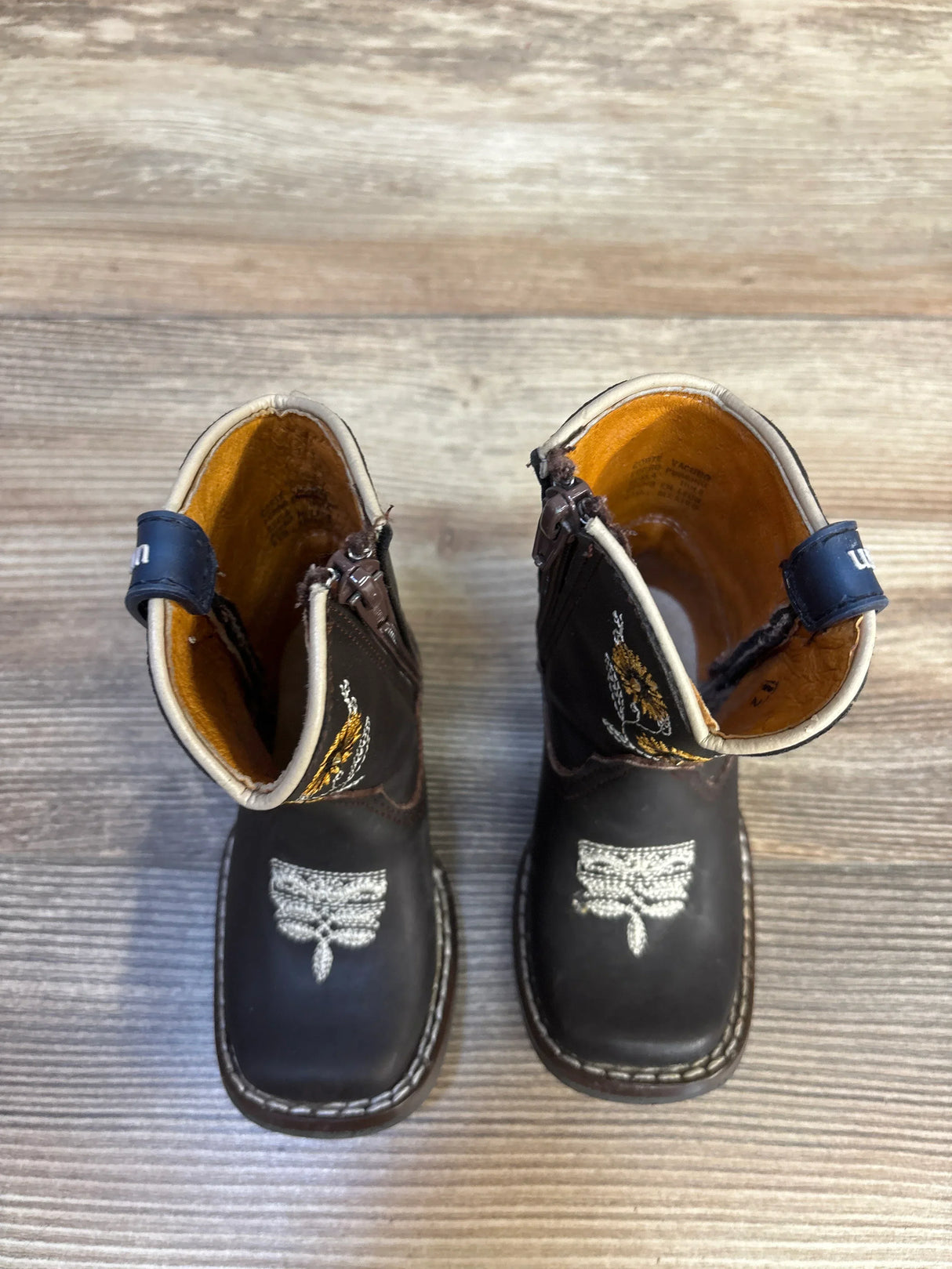 Side view of Rockem embroidered sunflower toddler western boots size 5/6C showing side zipper and blue ankle straps on wood floor