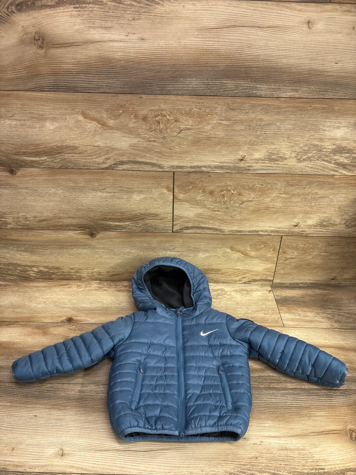 Blue Nike puffer zip jacket for baby size 18m on a wooden background