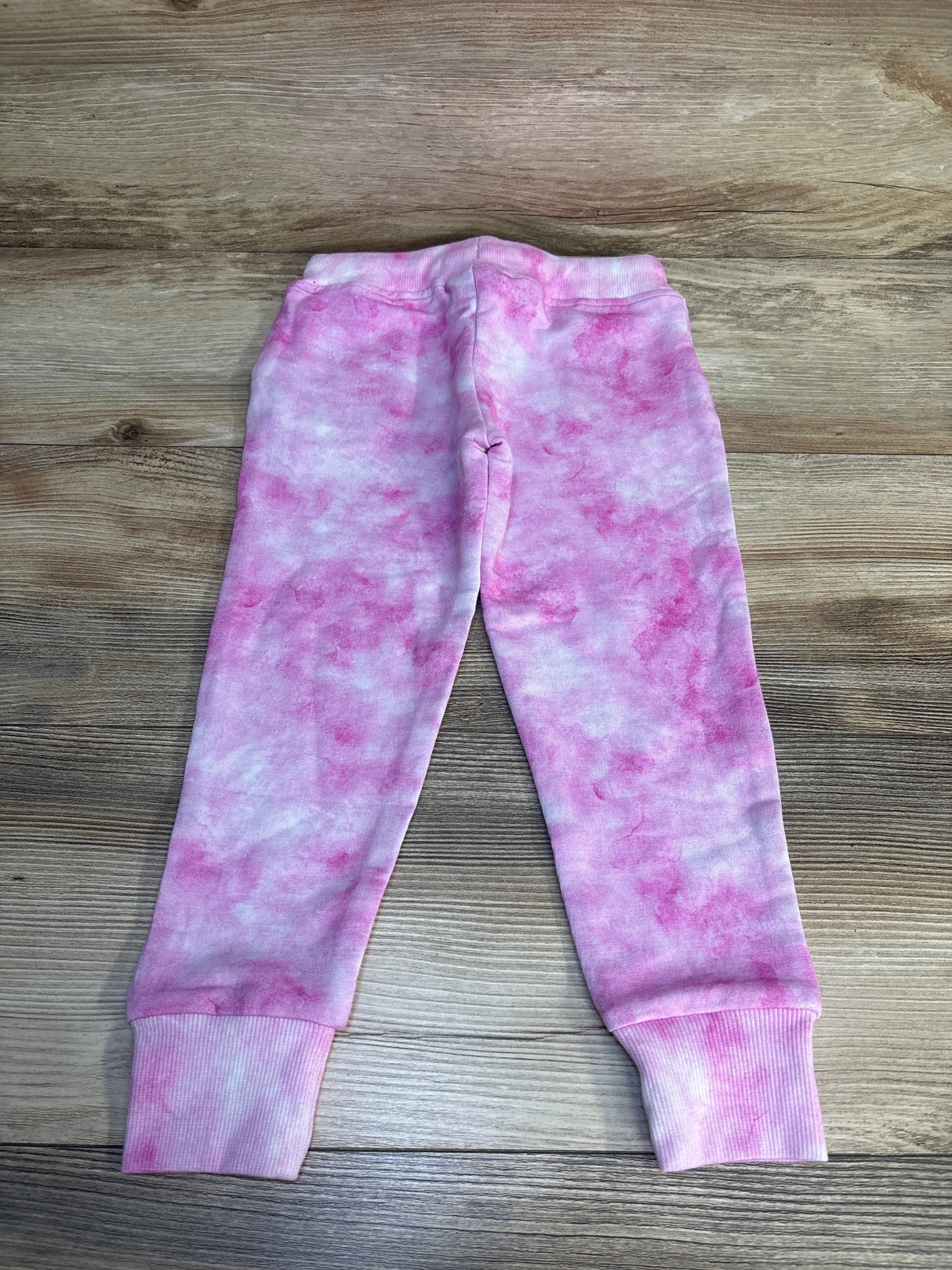 Pink and white tie-dye toddler leggings on wood background