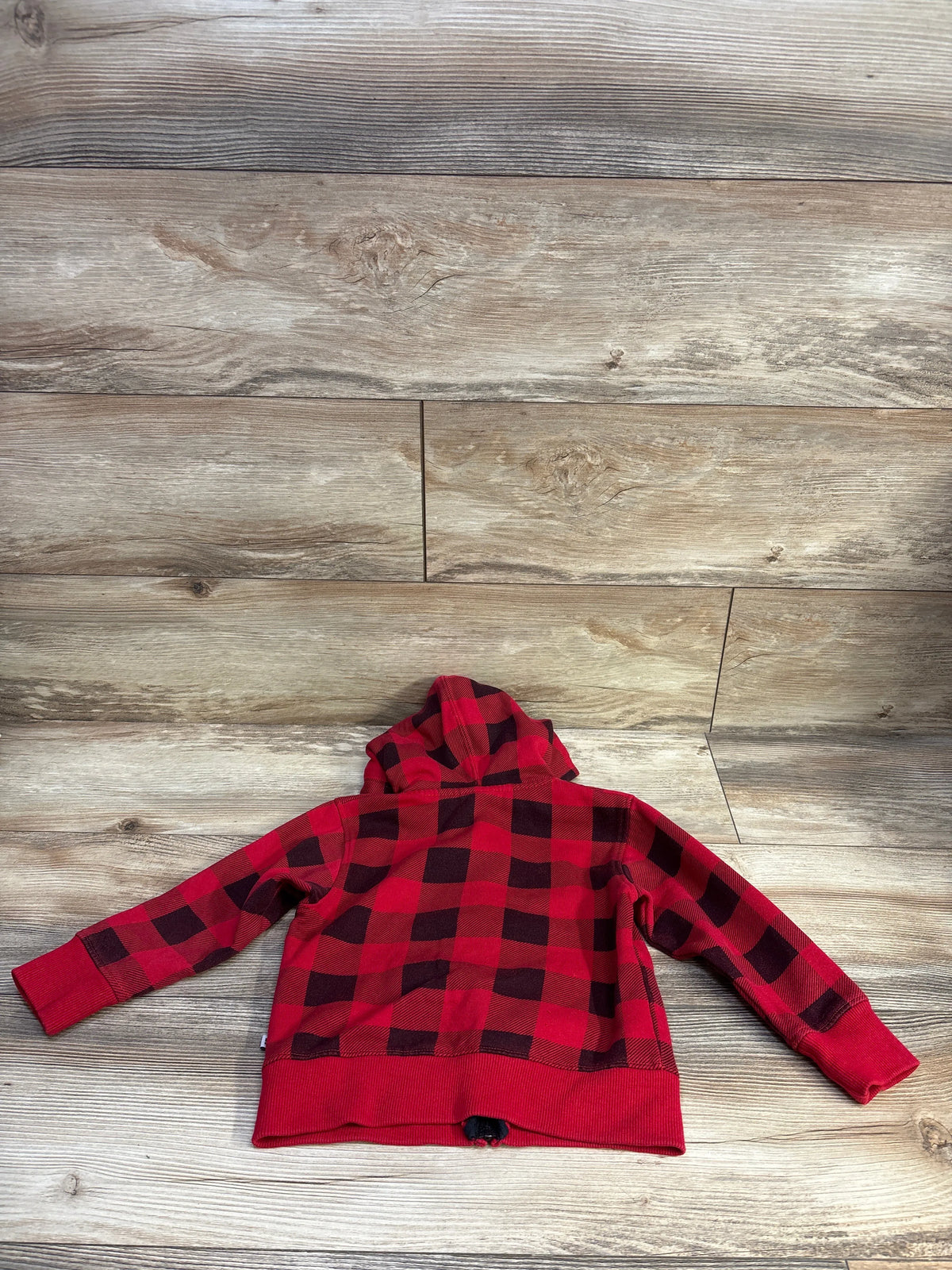 Back view of DC Shoes toddler red-black plaid zip-up hoodie showing hood and ribbed cuffs on wood background