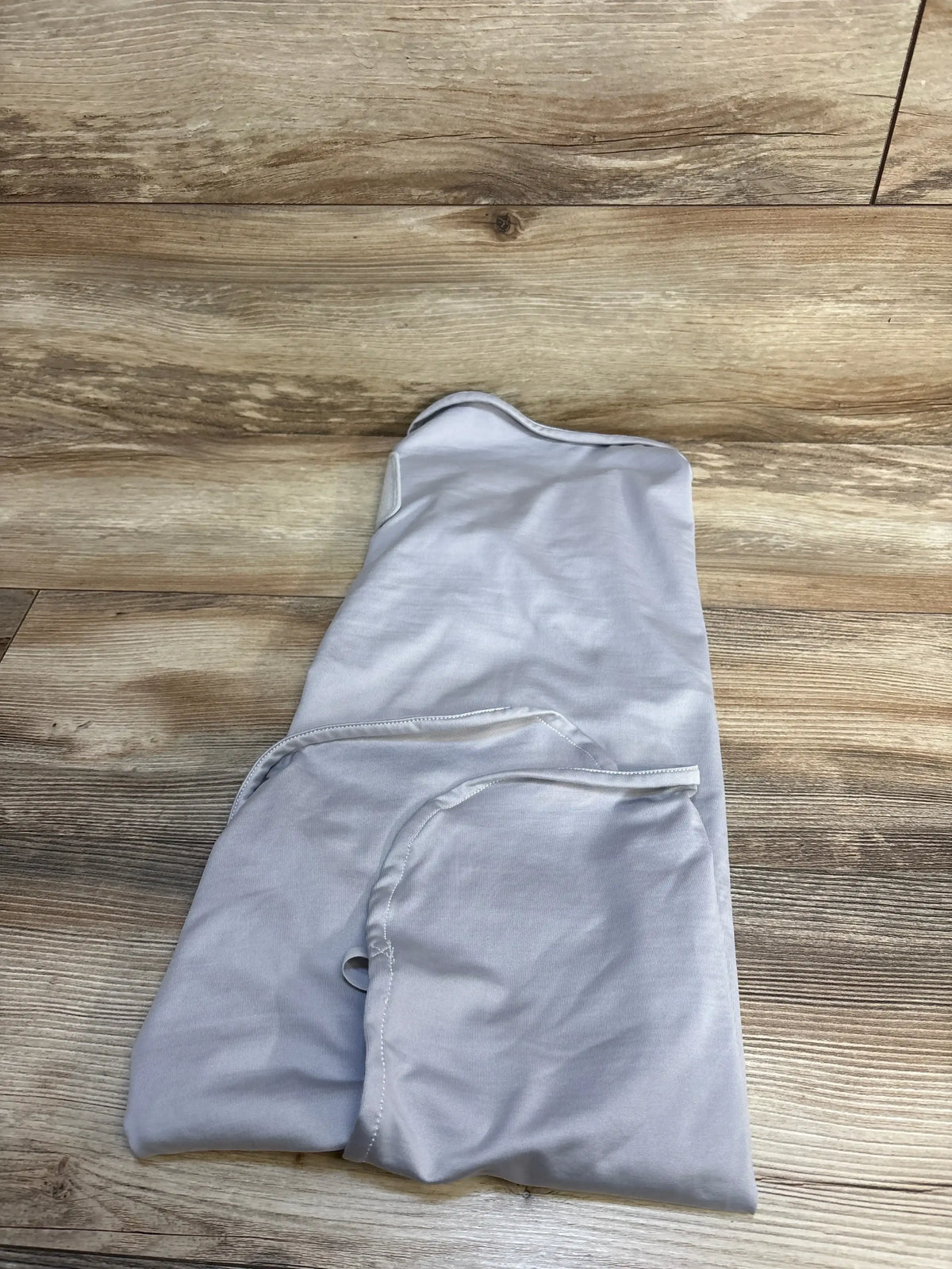 Light gray baby sleep sack on wooden floor, soft fabric with zipper detail