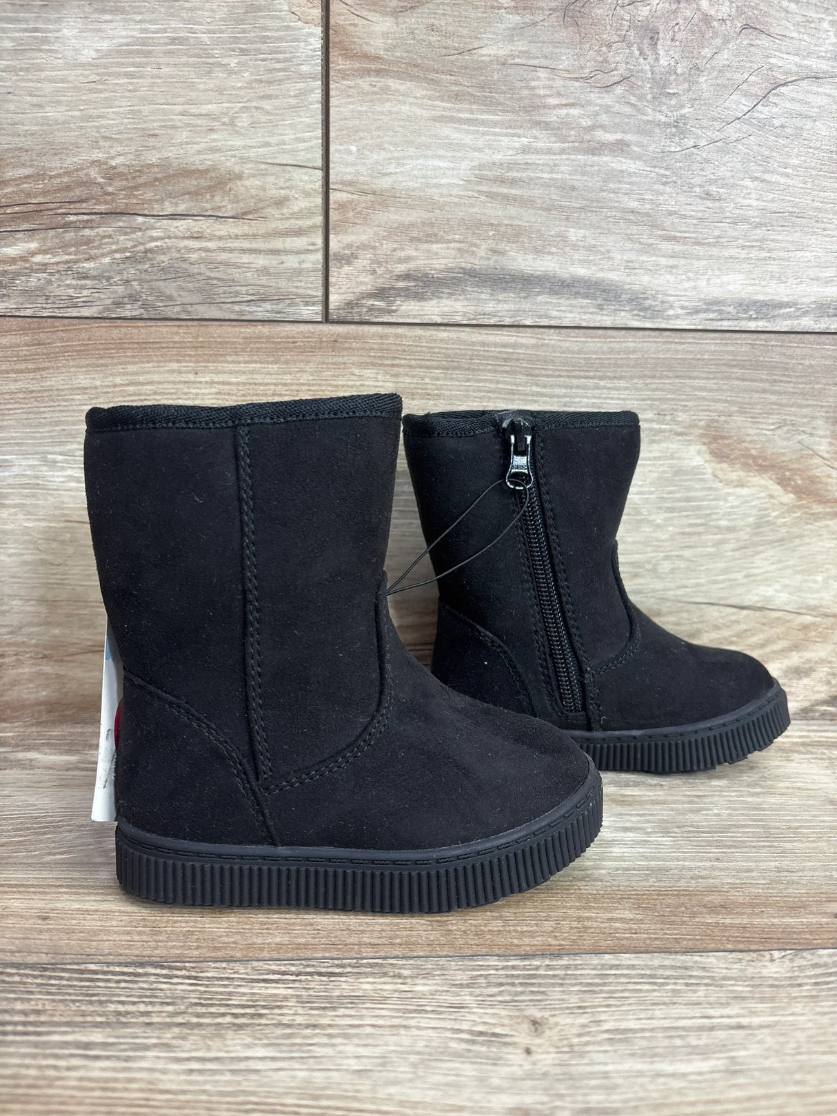 Black suede kids boots with side zipper on wood background, children's footwear