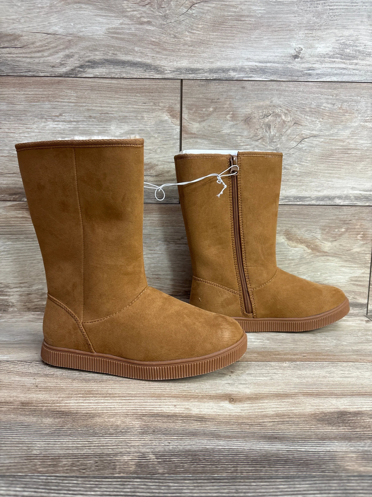 Kids tan suede winter boots with zipper, rubber sole, on wood background