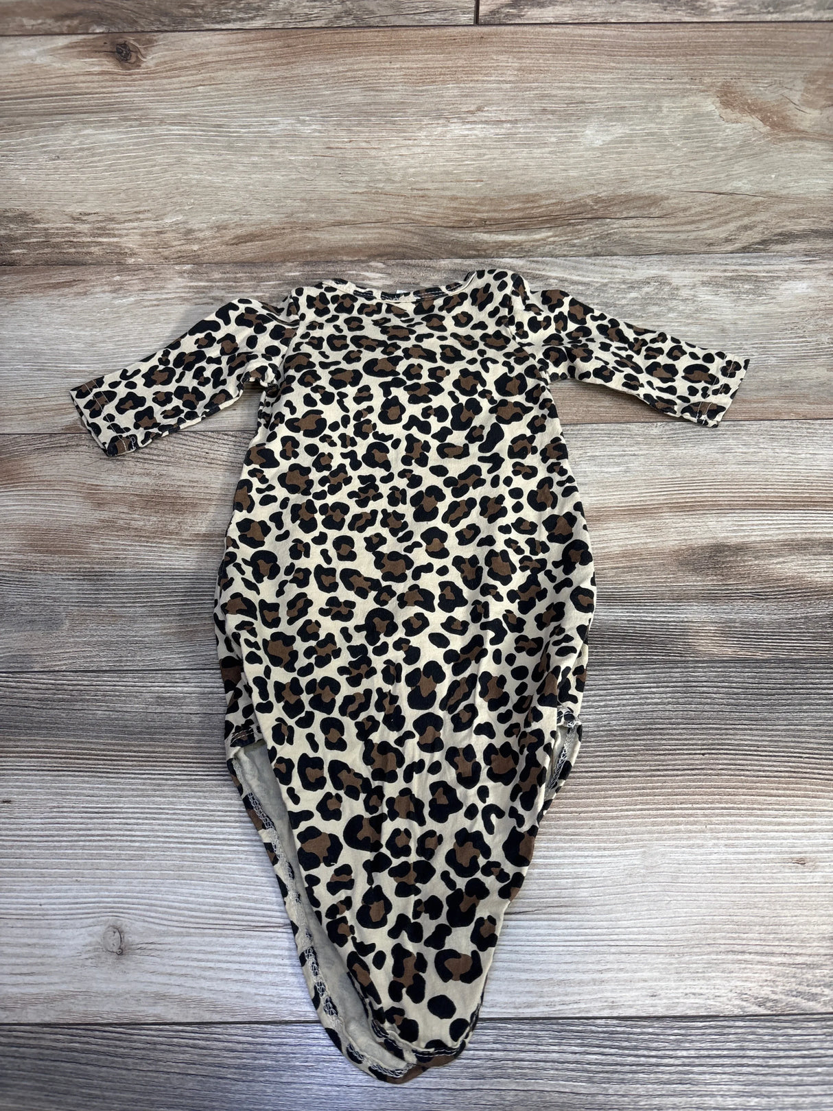 Leopard print baby onesie with long sleeves on wood background