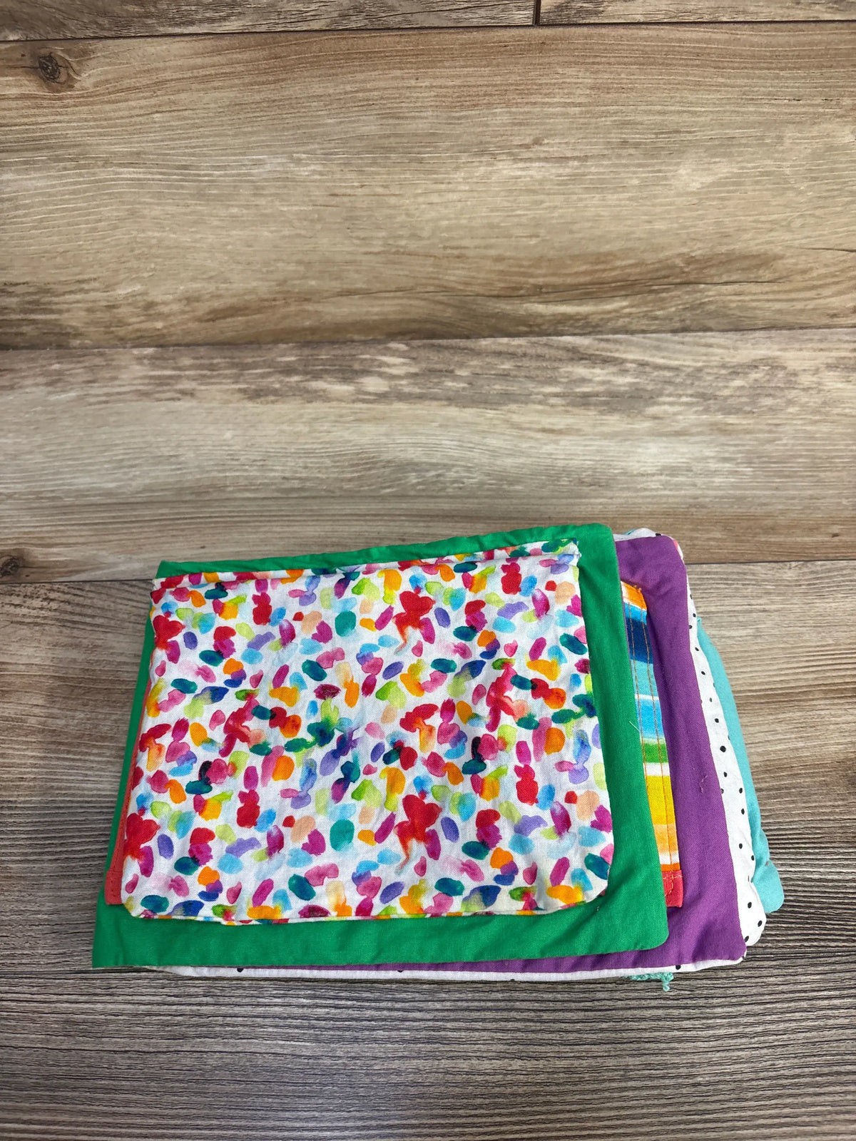Top view of Lovevery Soft Book showcasing colorful tactile fabric pages with a wooden floor background