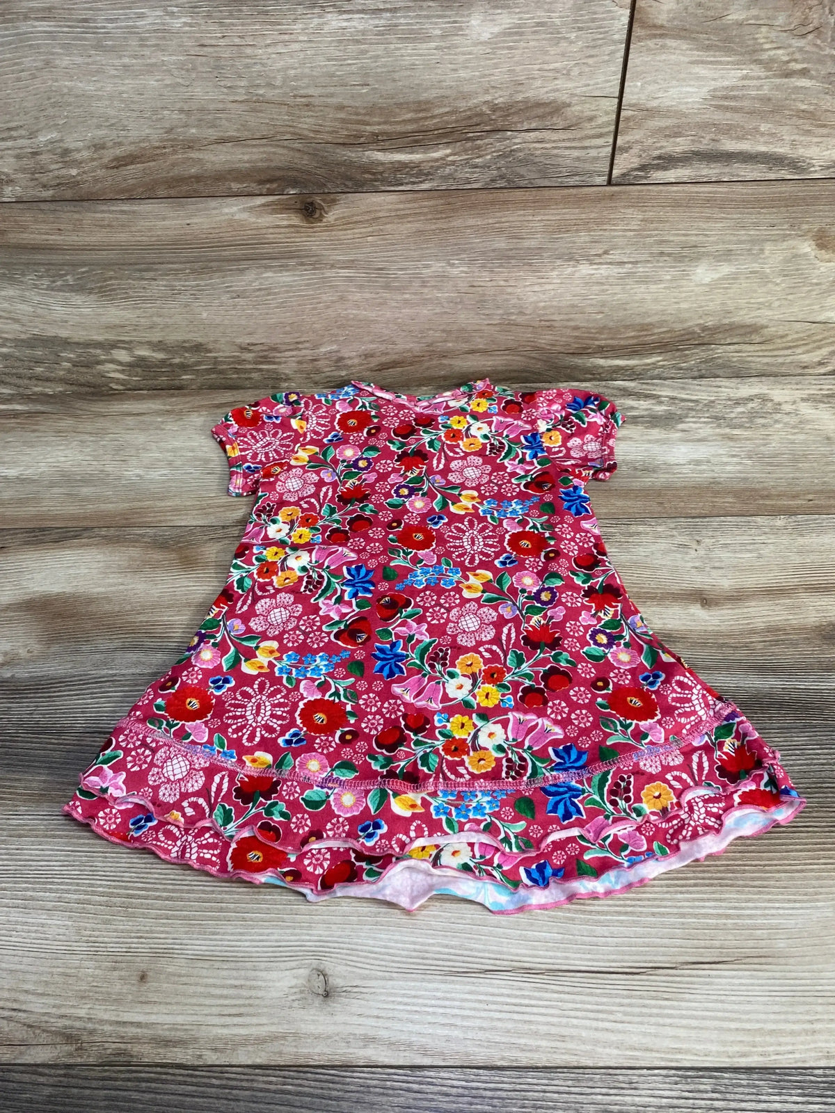 Flat lay of Oilily pink 2T toddler floral dress with short puff sleeves, ruffle hem and flowers on wood background