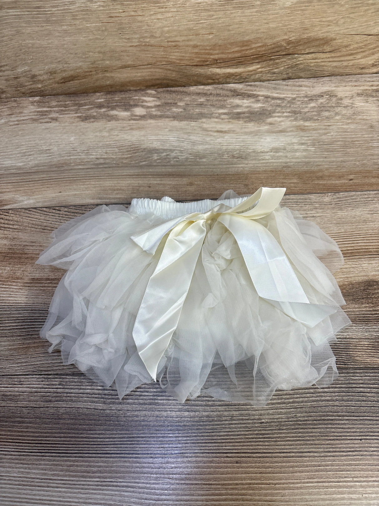 White baby tutu skirt with satin ribbon bow on wooden background