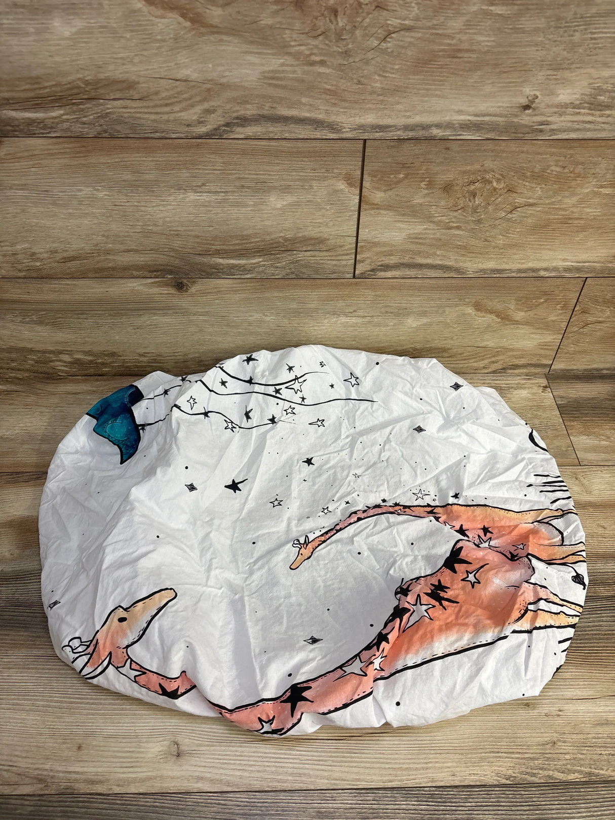 Crinkled white fabric with whimsical orange giraffe and star print on wood floor