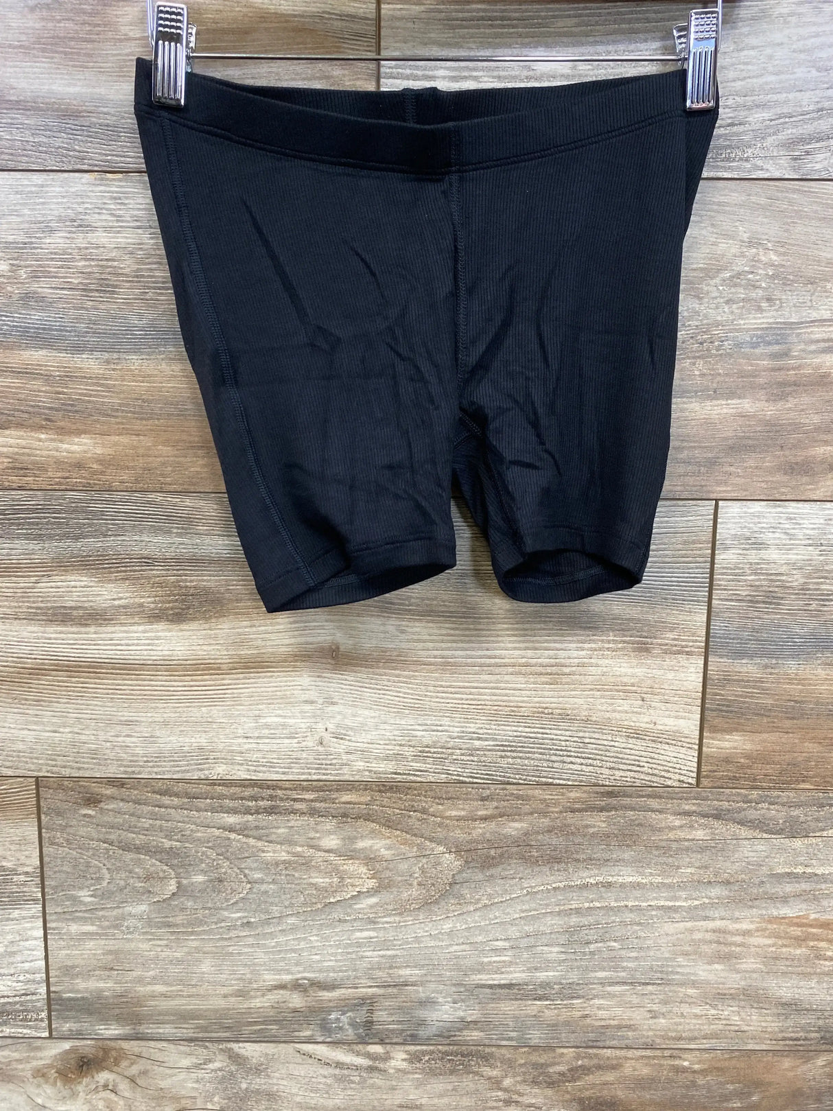 Front view of black Gap maternity ribbed PJ shorts showing elastic high-rise waistband and ribbed texture on wood floor background
