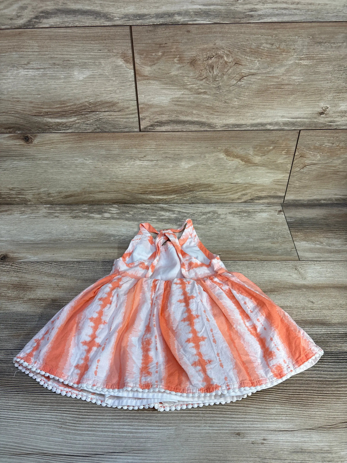 Front view of Max Studio peplum tank top in orange showcasing the peplum ruffle at the waist on a wood floor