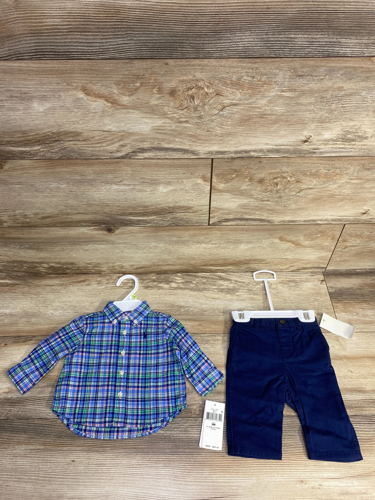 Flat lay of Ralph Lauren 2-piece baby boy size 3M blue-green plaid button-down shirt and navy pants on wood floor