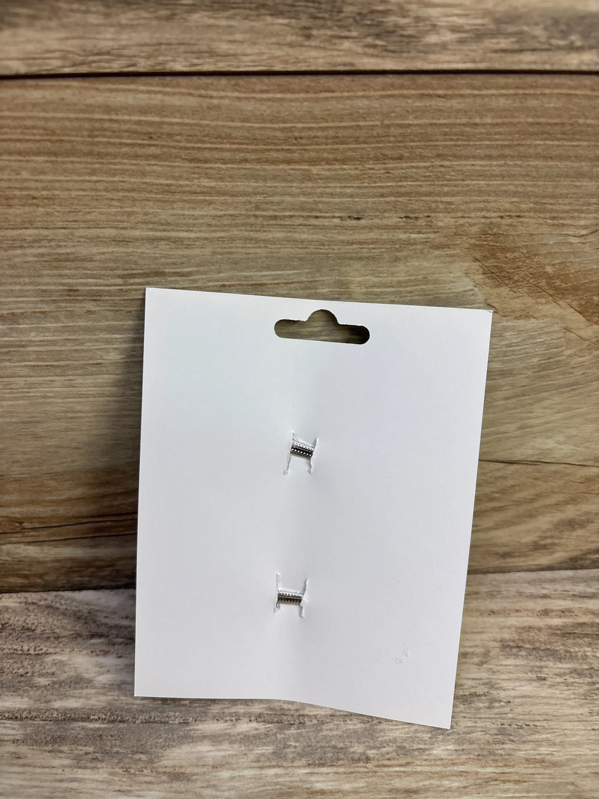 Front view of 2 grey hair bow clips showcasing silver alligator clip backs on a white display card with wood backdrop