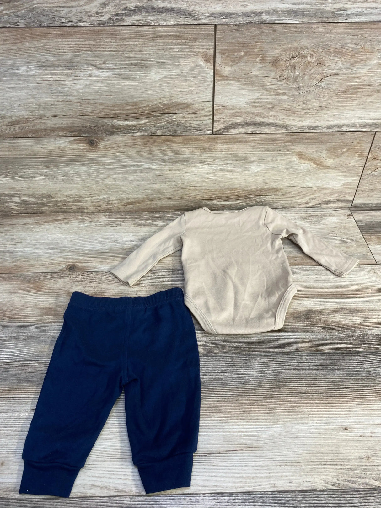Back view of Tommy Hilfiger two piece set with beige long sleeve bodysuit and navy blue pants on wood plank floor
