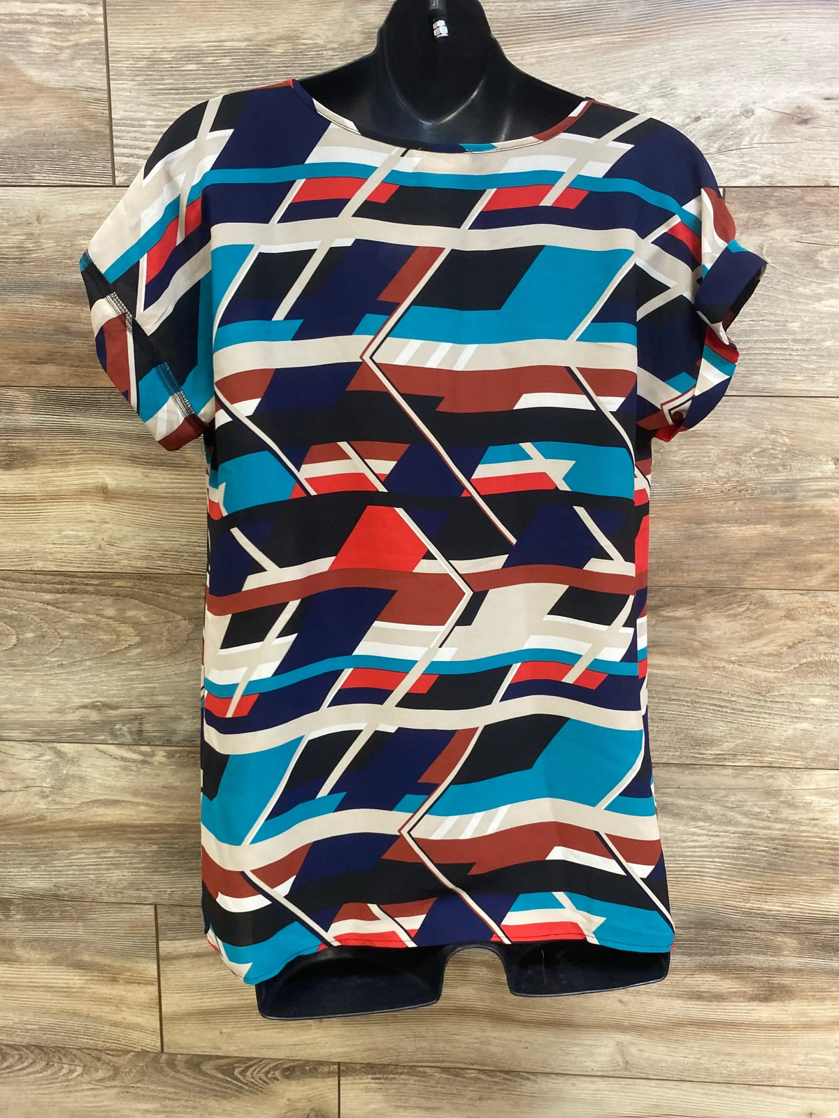 Front view of Motherhood Maternity v-neck shirt with geometric pattern on a black mannequin over wood-look flooring