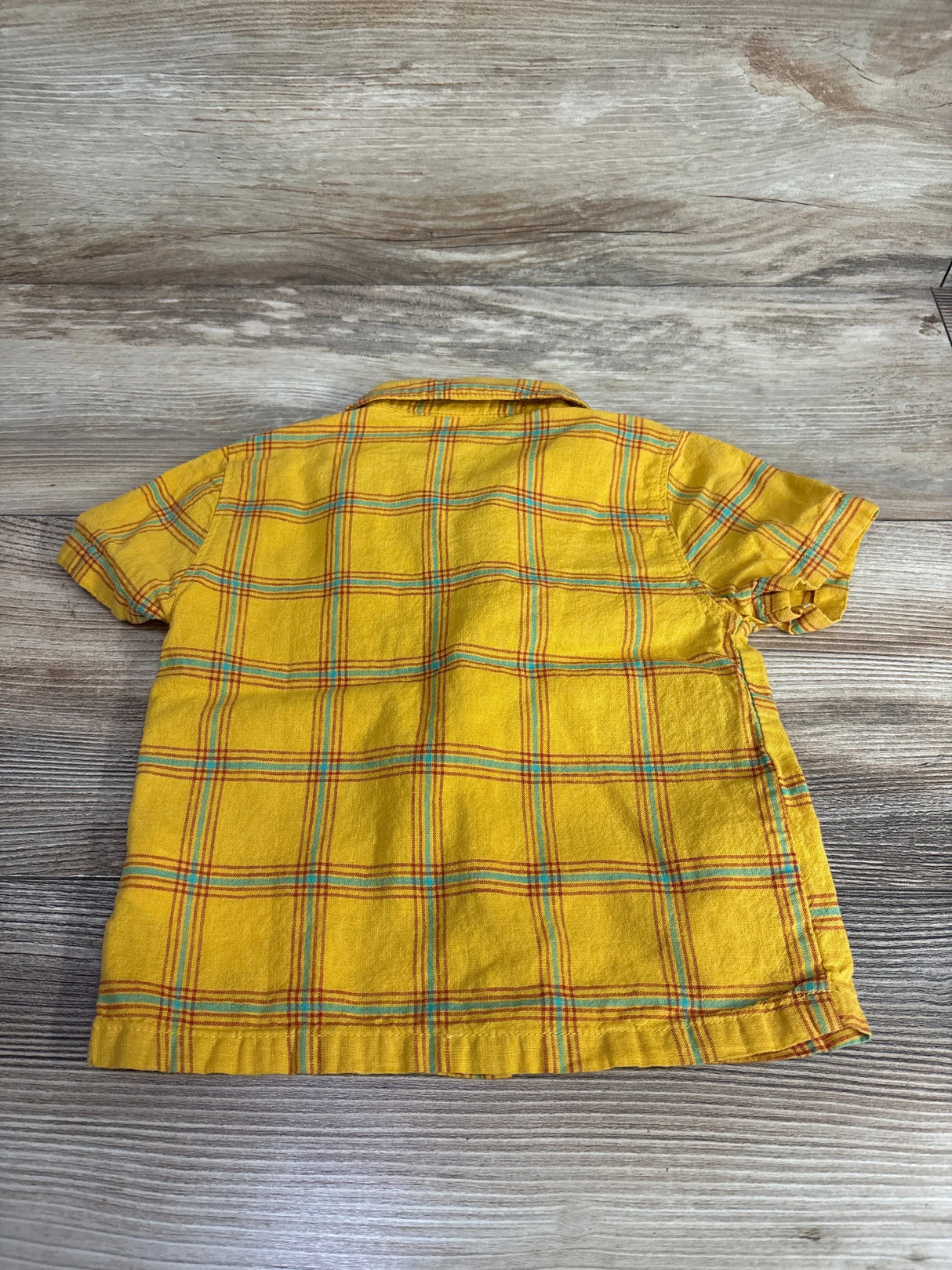 Yellow plaid short sleeve kids shirt on wood background