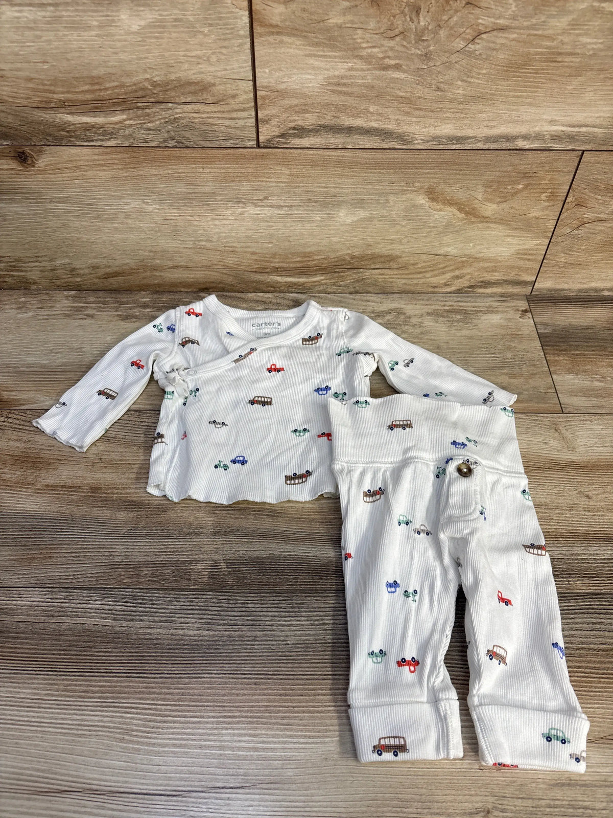 Top-down view of white ribbed kimono top and matching bottoms showcasing colorful vehicle print on a wood floor