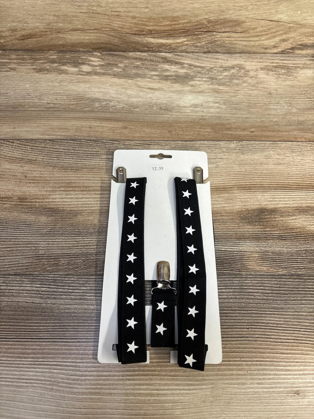 Front view of Parquet star print suspenders showcasing black straps with white stars and metal clips on a wood surface