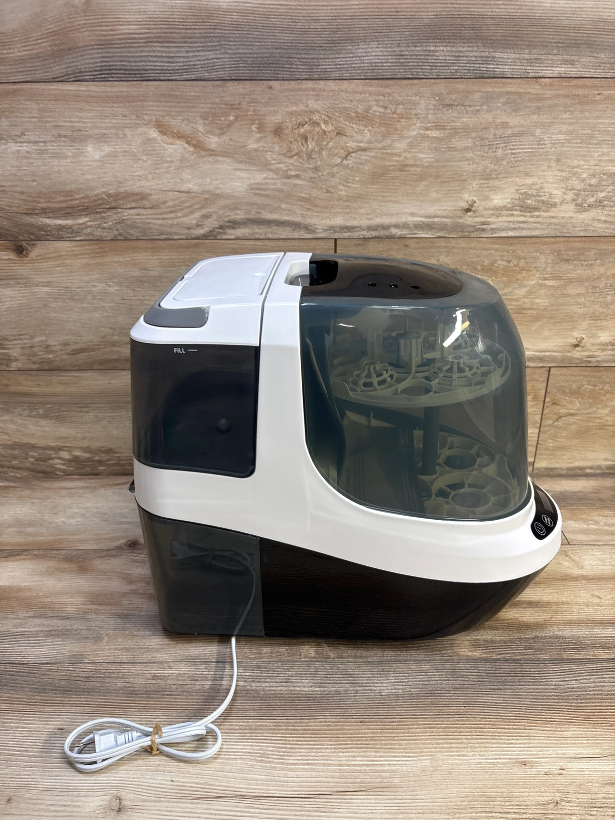 Right side view of Baby Brezza Bottle Washer Pro showing transparent chamber and coiled cord on wood backdrop