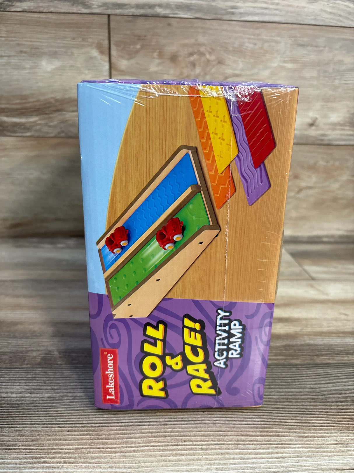 Front view of Activity Ramp box showing headline ROLL AND RACE, two textured ramps and two red cars on wood background