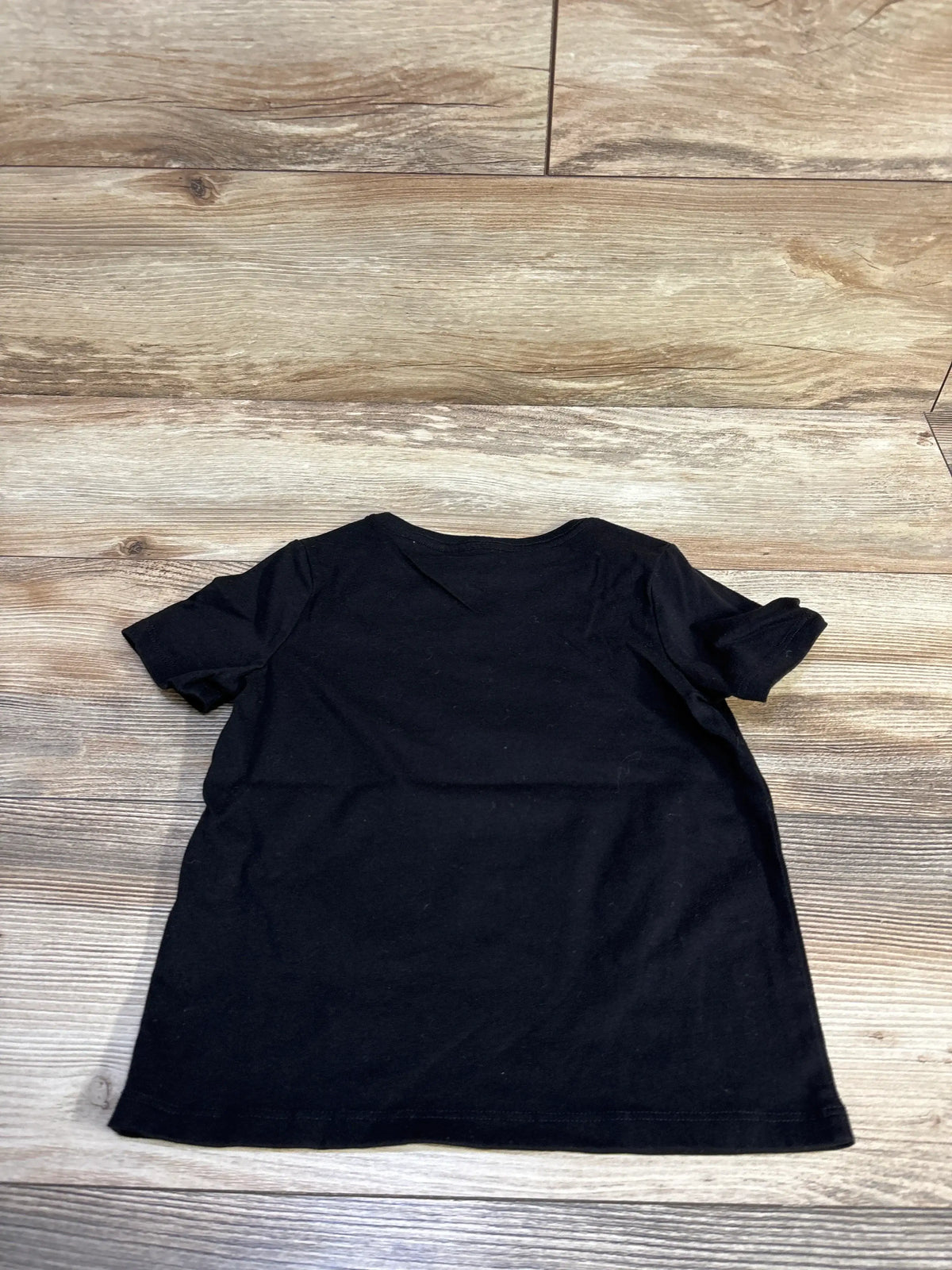 Back view of Wonder Nation Pumpkin Season toddler black t-shirt showing plain back and short sleeves on wood floor