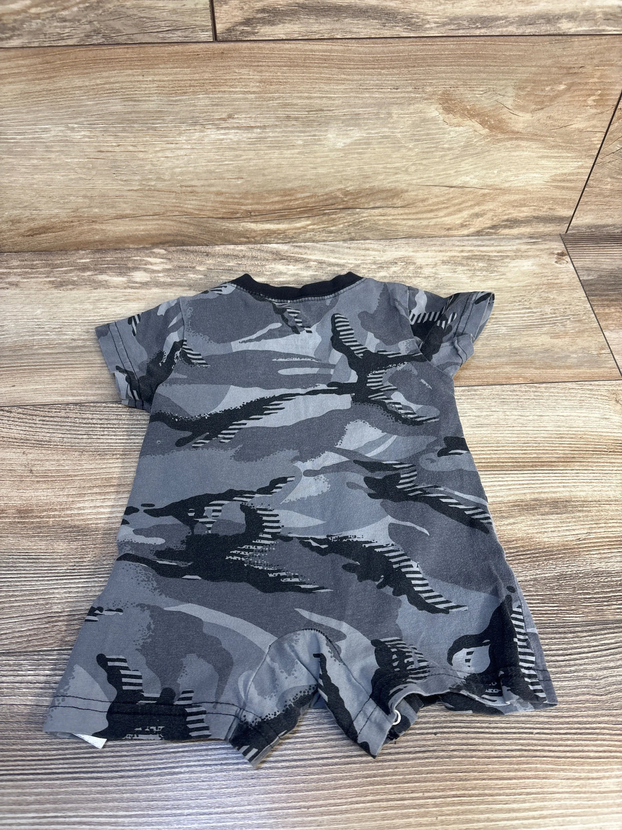 Gray camouflage baby romper with short sleeves on wooden floor