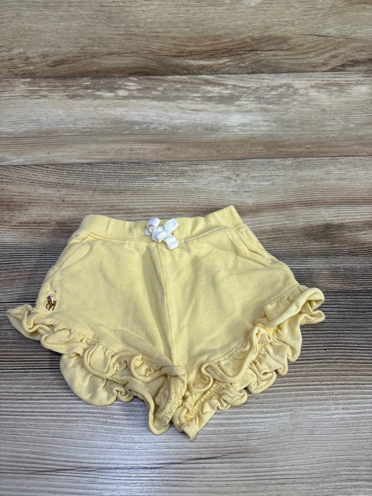 Yellow Me n Mommy To Be pull-on ruffle shorts for baby size 6m on a wood background