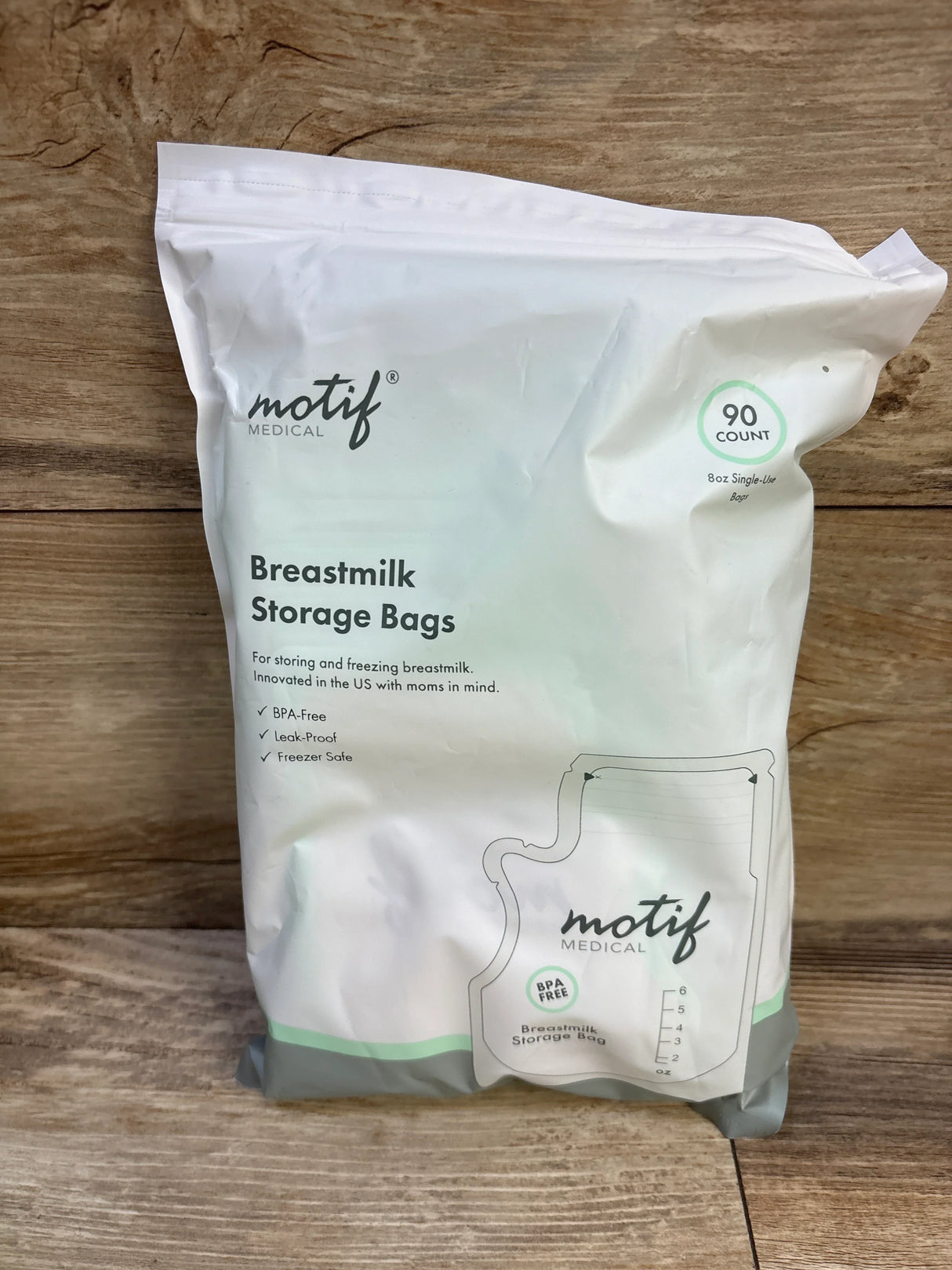Front view of Motif Medical breastmilk storage bags, 90 count 8 oz, showing BPA free leak proof features on wooden background