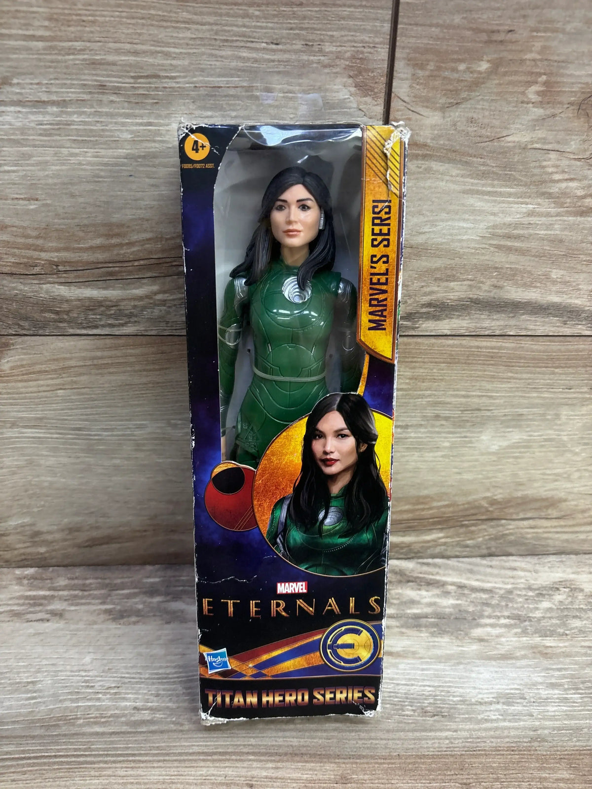 Front view of Sersi Titan Hero Series action figure in green suit, boxed on a wood background