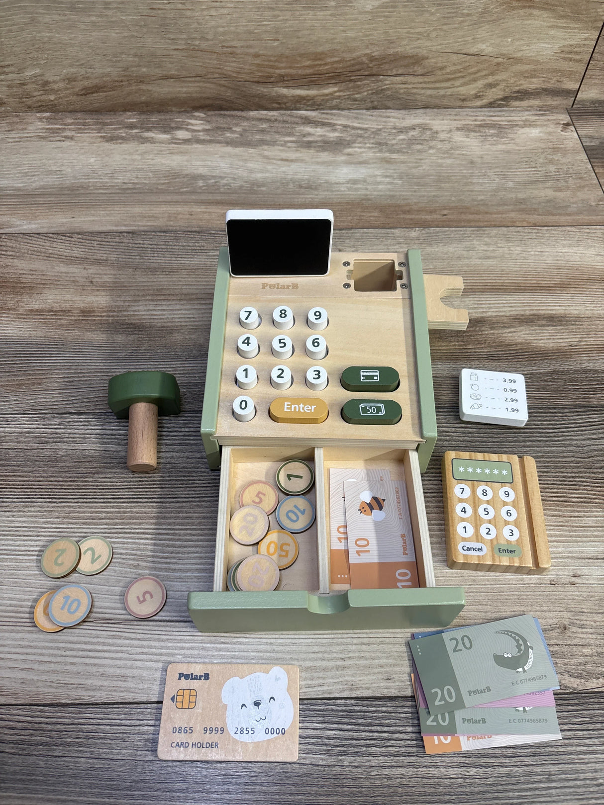Overhead view of PolarB wooden cash register playset with keypad, open drawer of coins and paper bills, toy card and reader