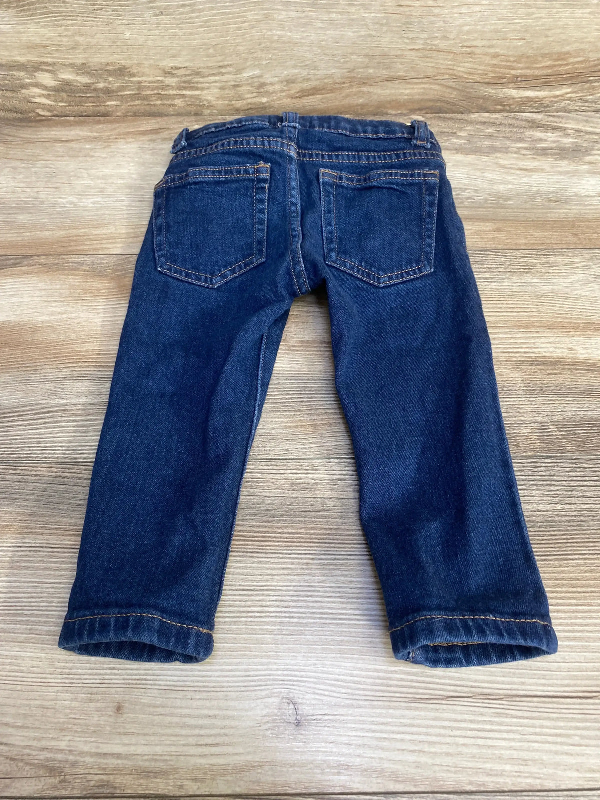 Back view of Jack denim slim jeans sz 18-24m showcasing dark wash blue denim with back pockets and slim fit on wood plank floor