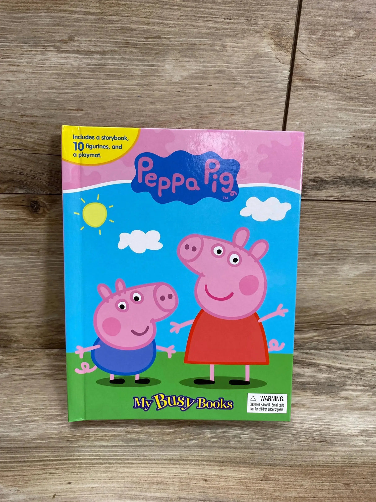 Front view of Peppa Pig My Busy Books board book showing Peppa and George on the cover with title text, on wood background