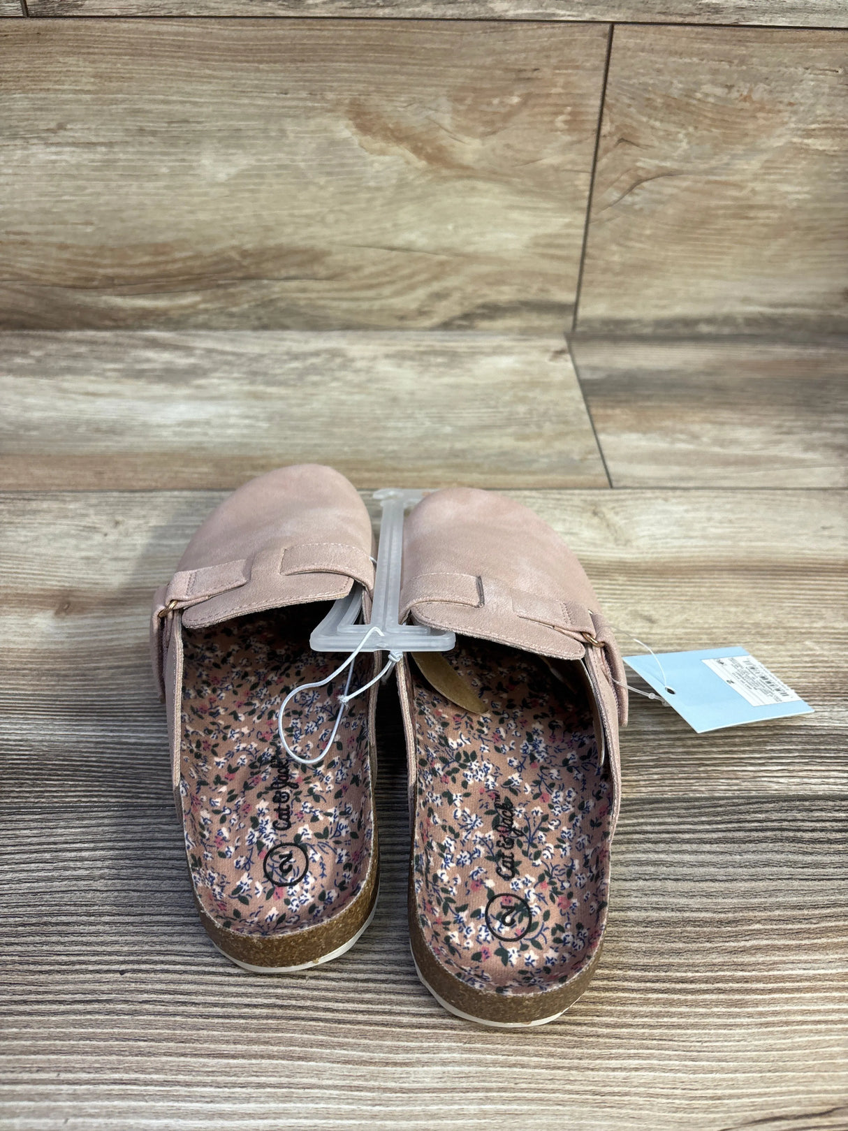Top-down view of Cat & Jack Perry toddler clogs in blush showcasing floral printed insoles, cork footbed, and adjustable strap on wood background